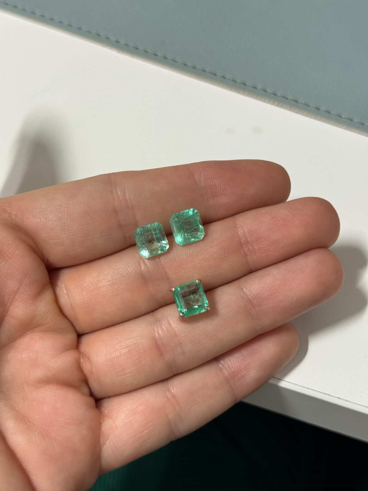 Pair of Colombian emerald stud earrings with 14K white gold setting, showcasing vibrant green gemstones in a close-up view.