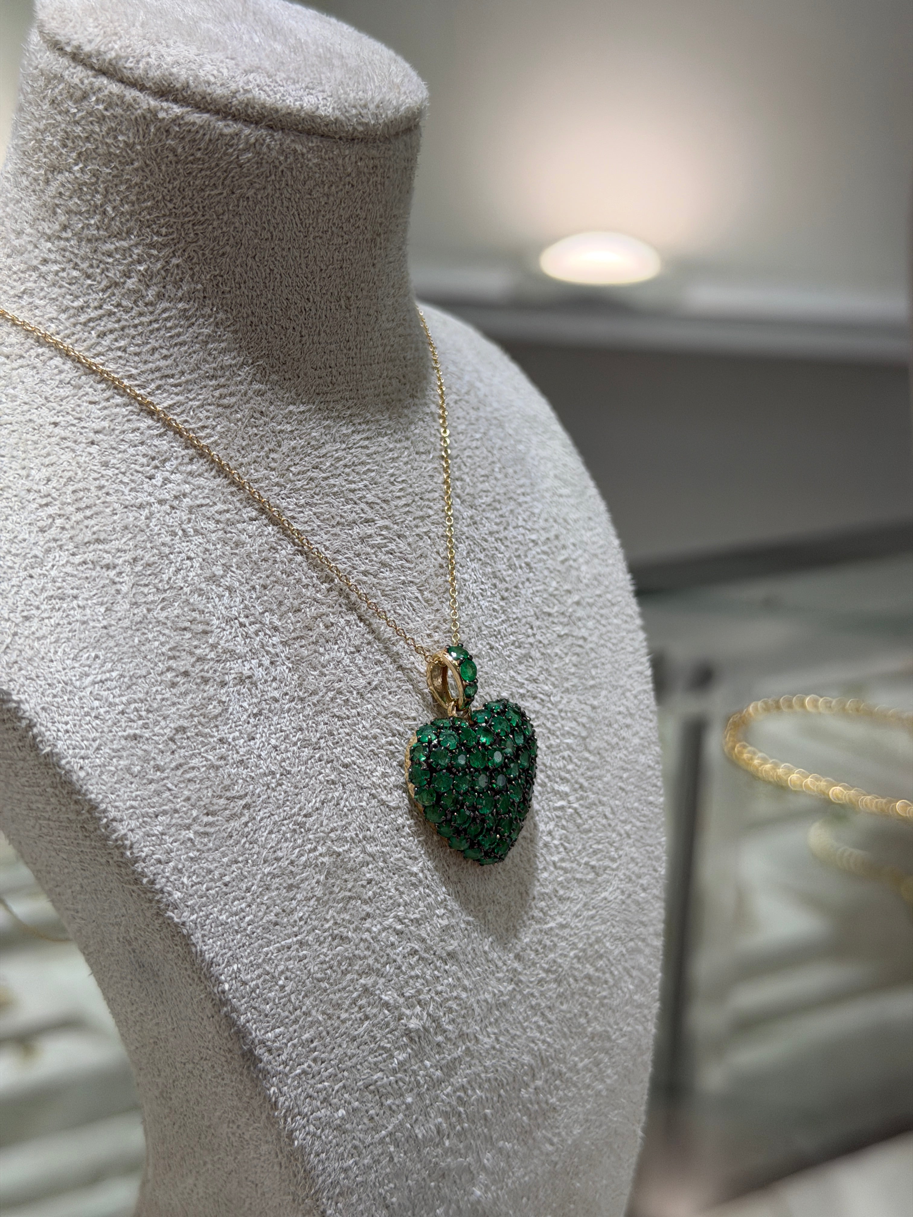 14K gold emerald cluster heart pendant with black rhodium, featuring multiple prongs and a heart-shaped design from JR Colombian Emeralds.