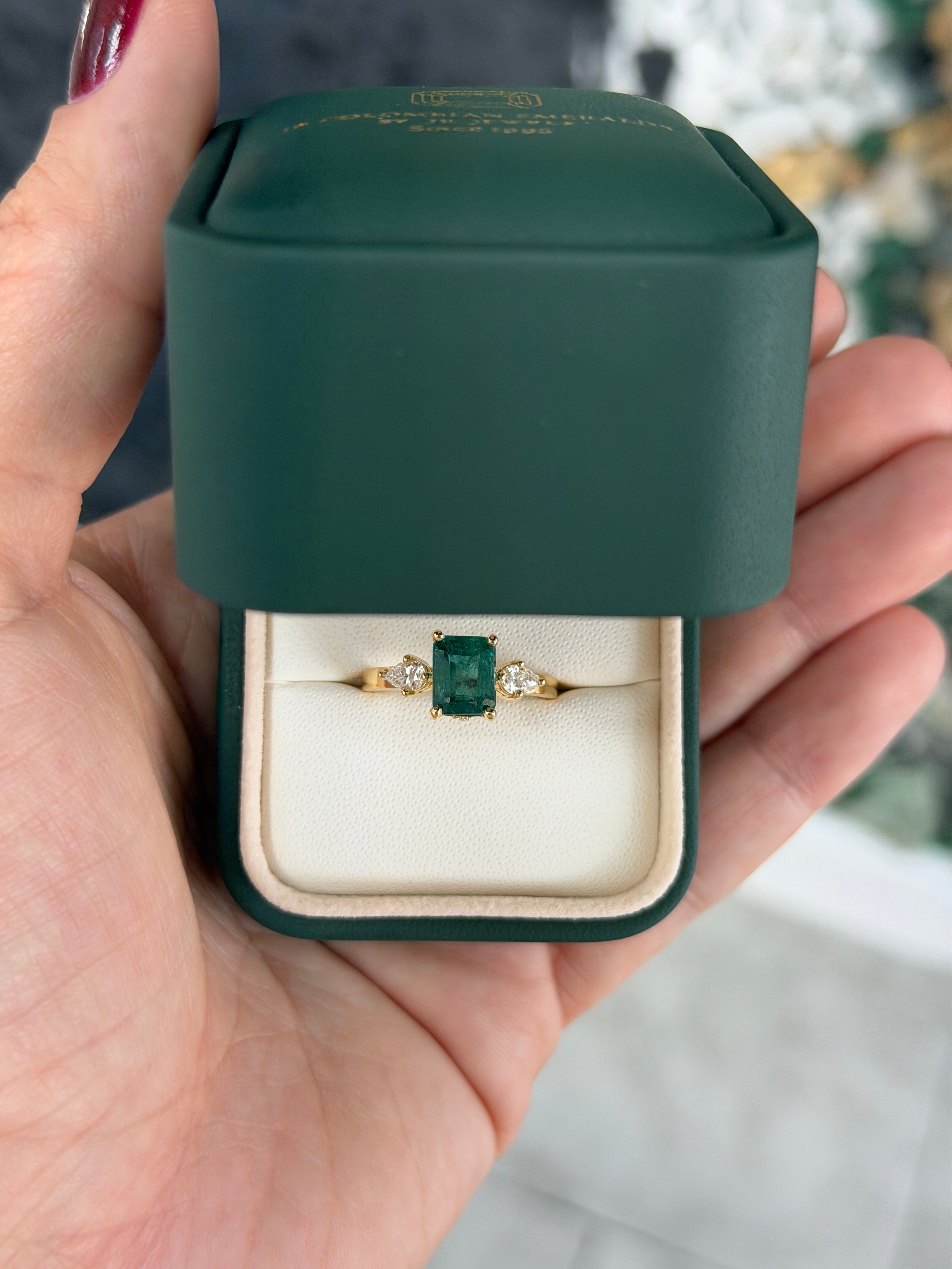 Emerald cut emerald and pear-shaped diamond three-stone ring with hidden diamond accents in 18K gold by JR Colombian Emeralds.