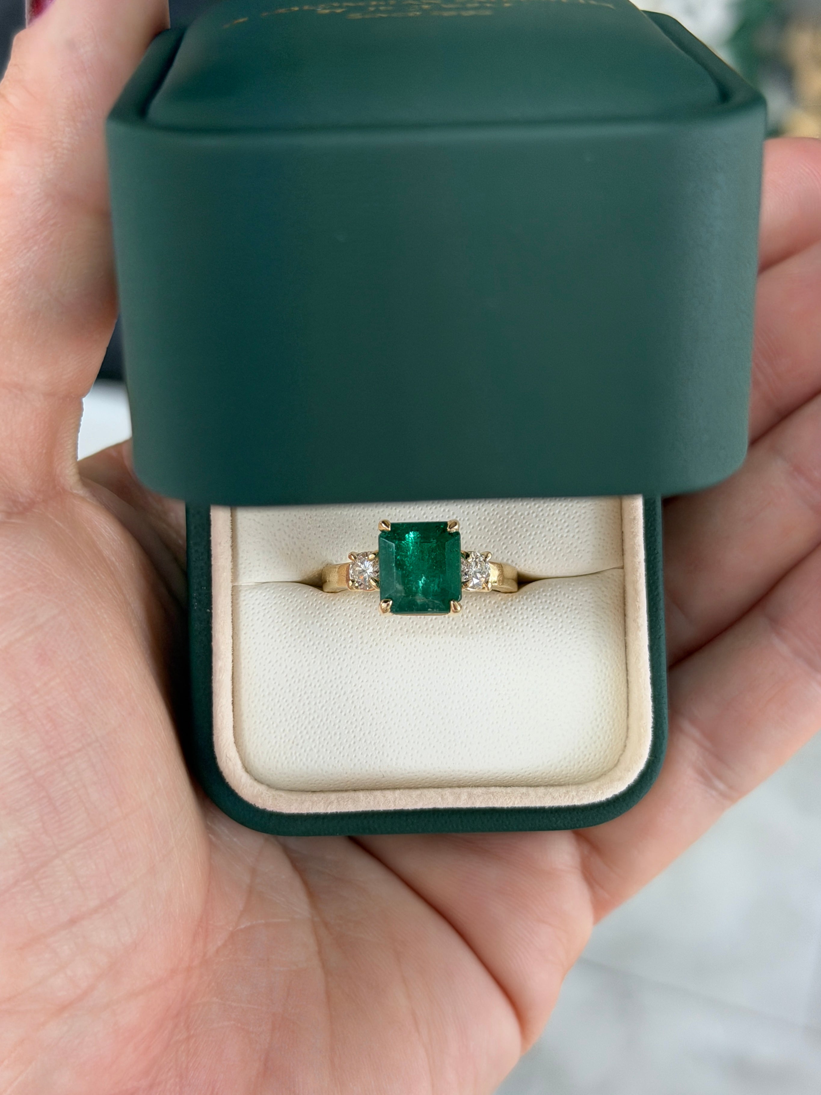 14K gold Zambian emerald cut three-stone engagement ring with round diamond side stones by JR Colombian Emeralds.