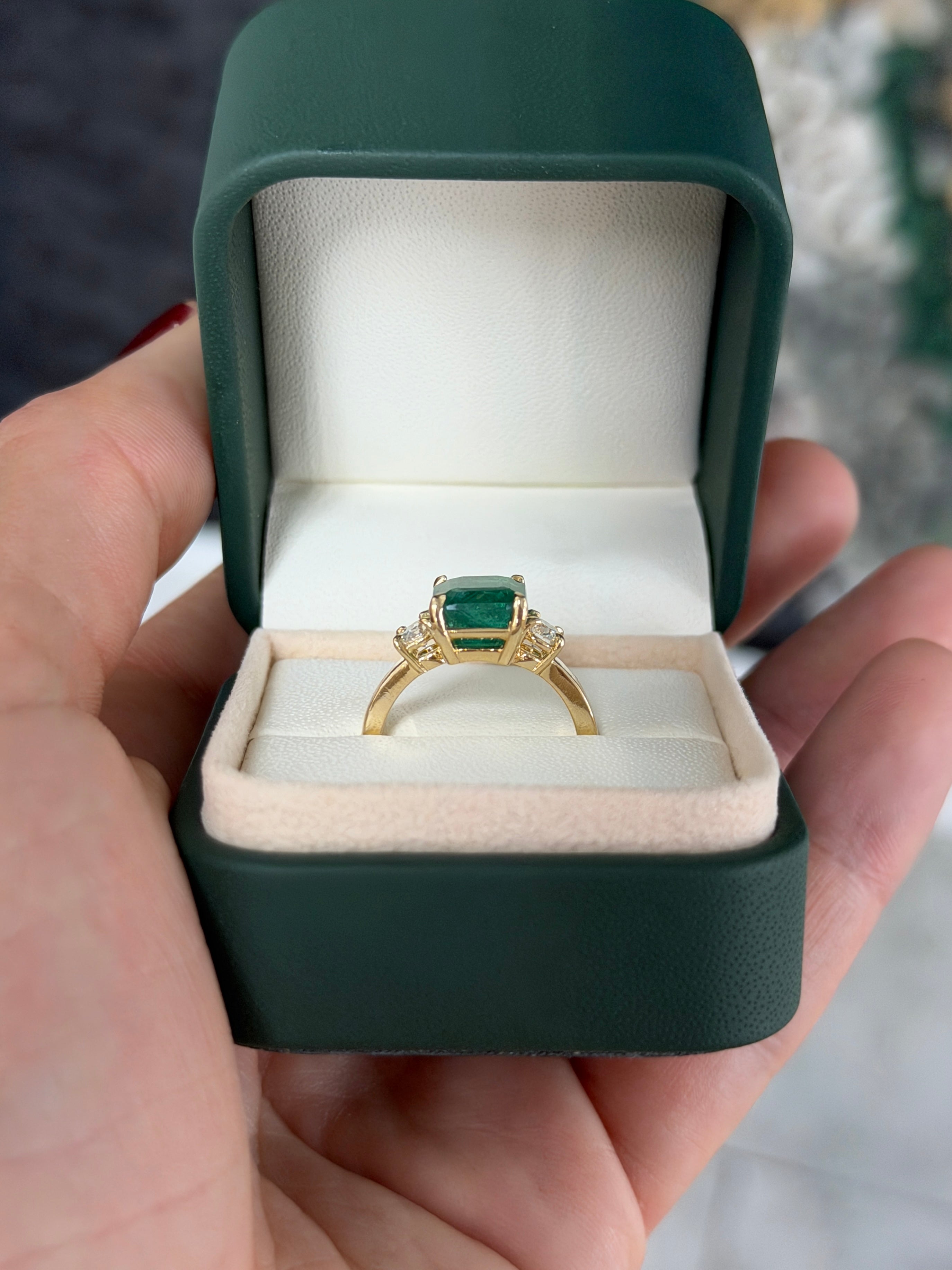 Zambian emerald cut three stone engagement ring with round diamond side stones in 14K gold by JR Colombian Emeralds.
