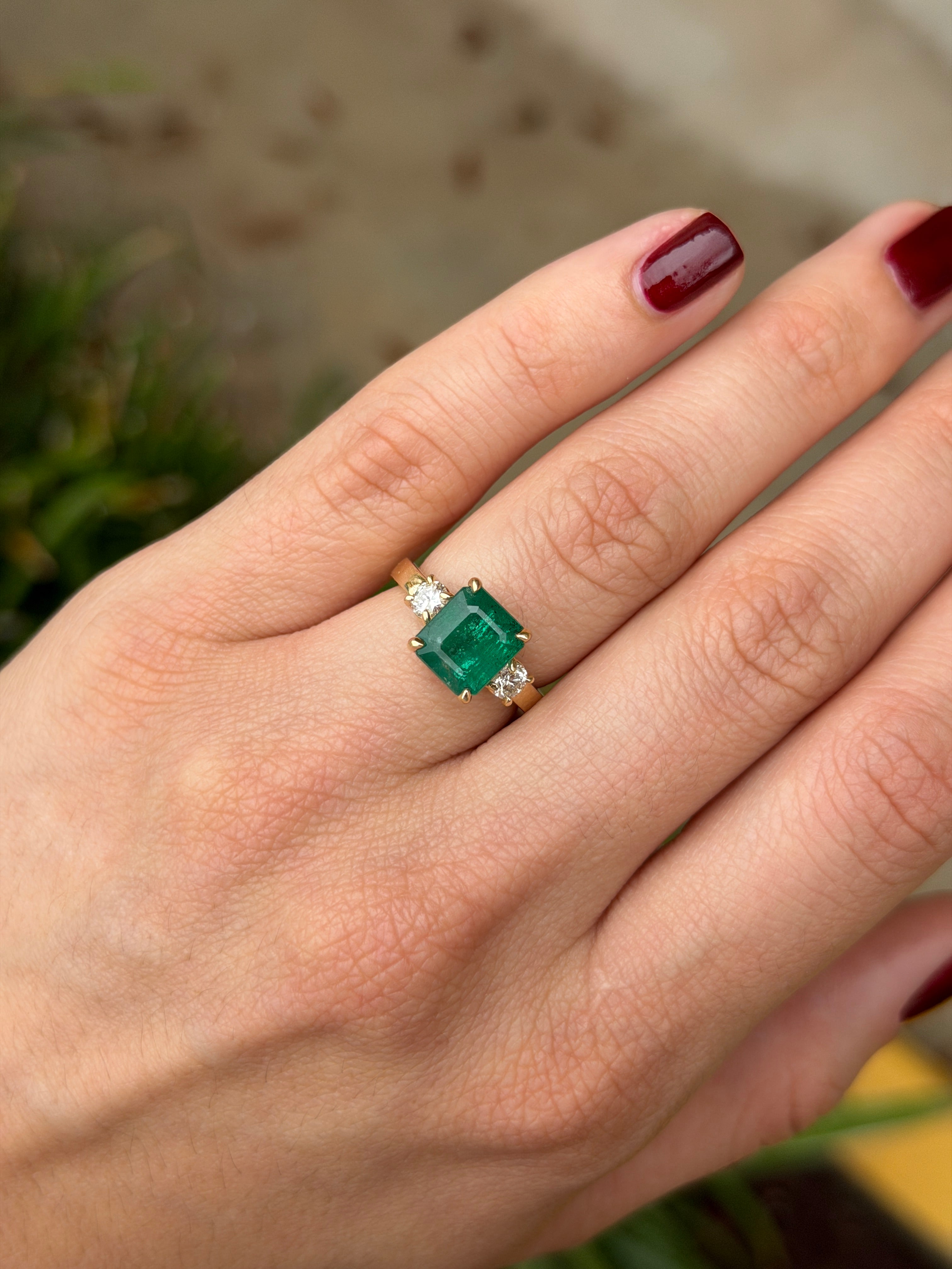 Zambian emerald cut three stone engagement ring with round diamond side stones in 14K gold by JR Colombian Emeralds.