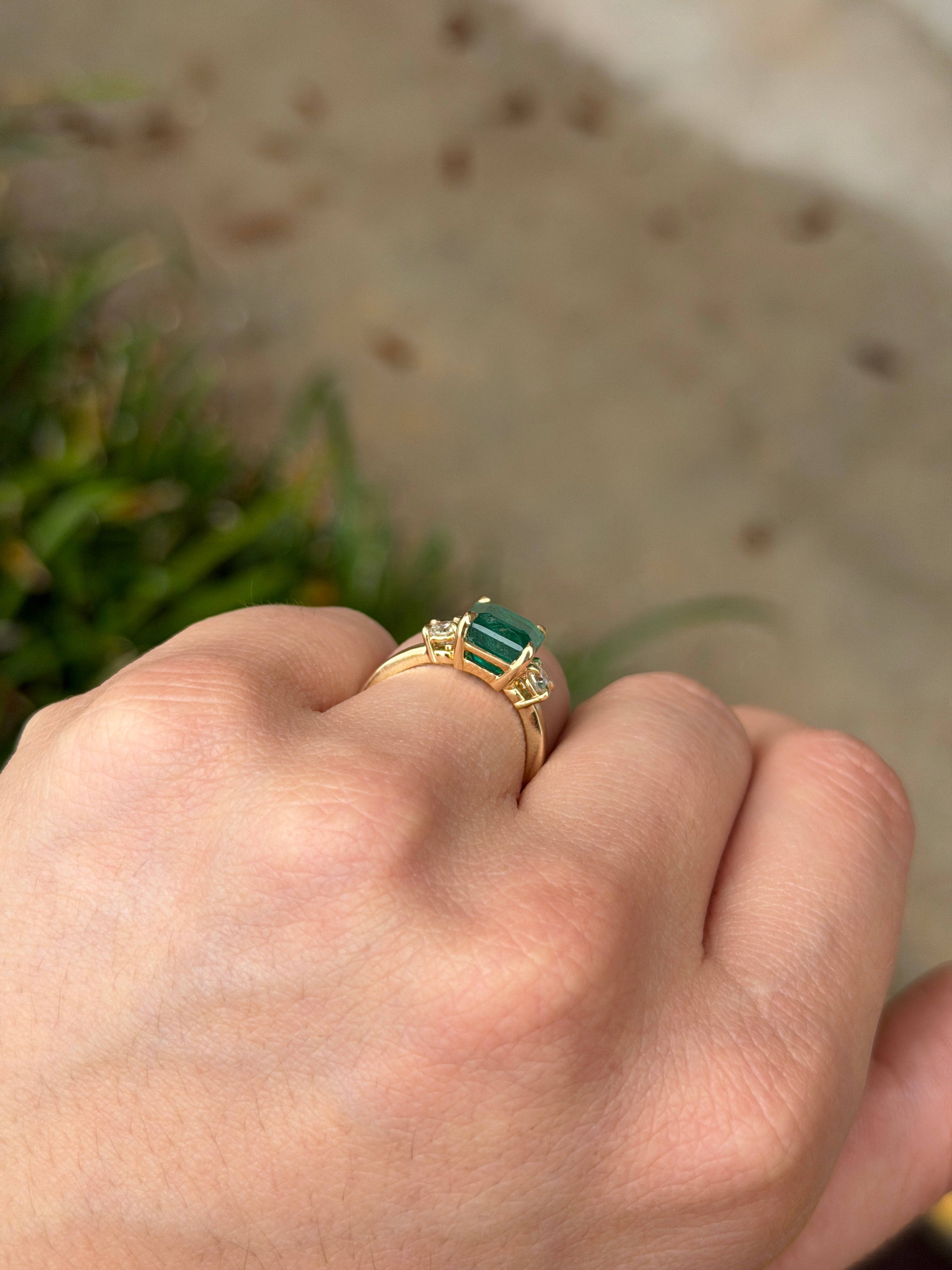Zambian emerald cut three stone engagement ring with round diamond side stones in 14K gold, from JR Colombian Emeralds.