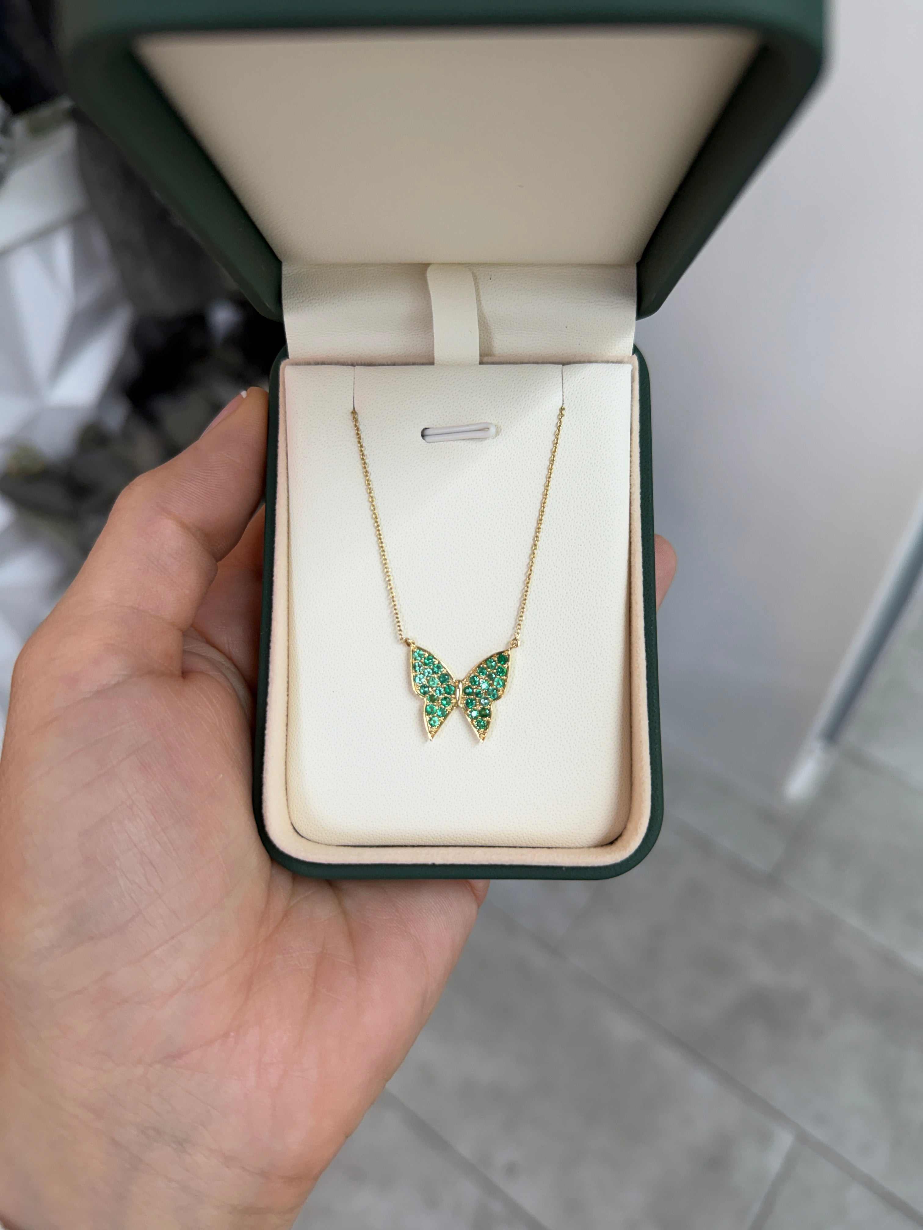 14K gold butterfly necklace with pave emerald accents, featuring a fluttering butterfly design, from JR Colombian Emeralds.
