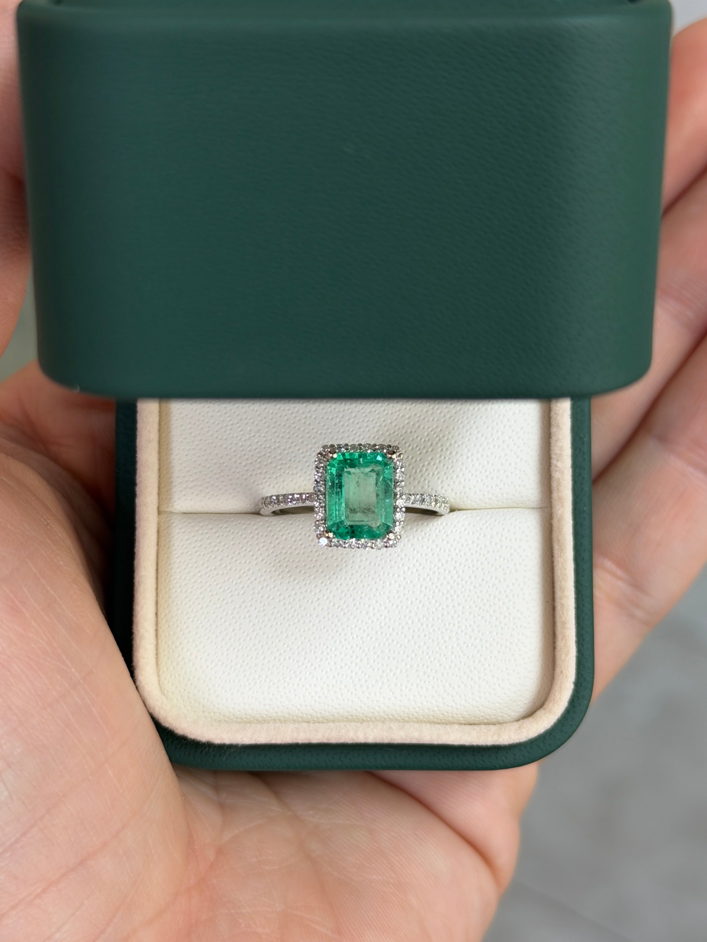 14K white gold engagement ring with 1.70tcw Colombian emerald and diamond halo, featuring a sparkling central emerald.