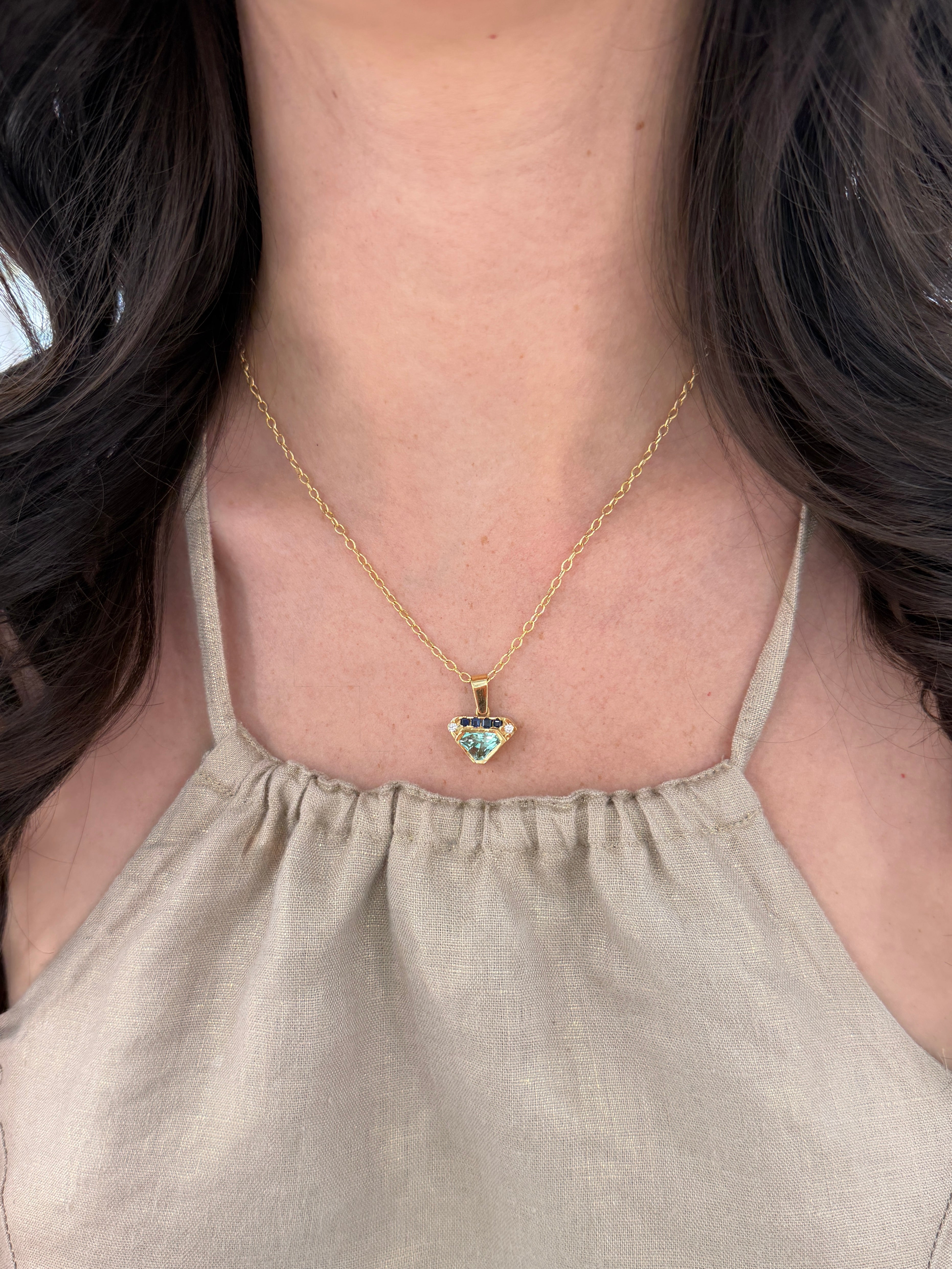 VVS clarity Colombian emerald shield cut pendant with blue sapphire and diamonds, featuring JR Colombian Emeralds branding.