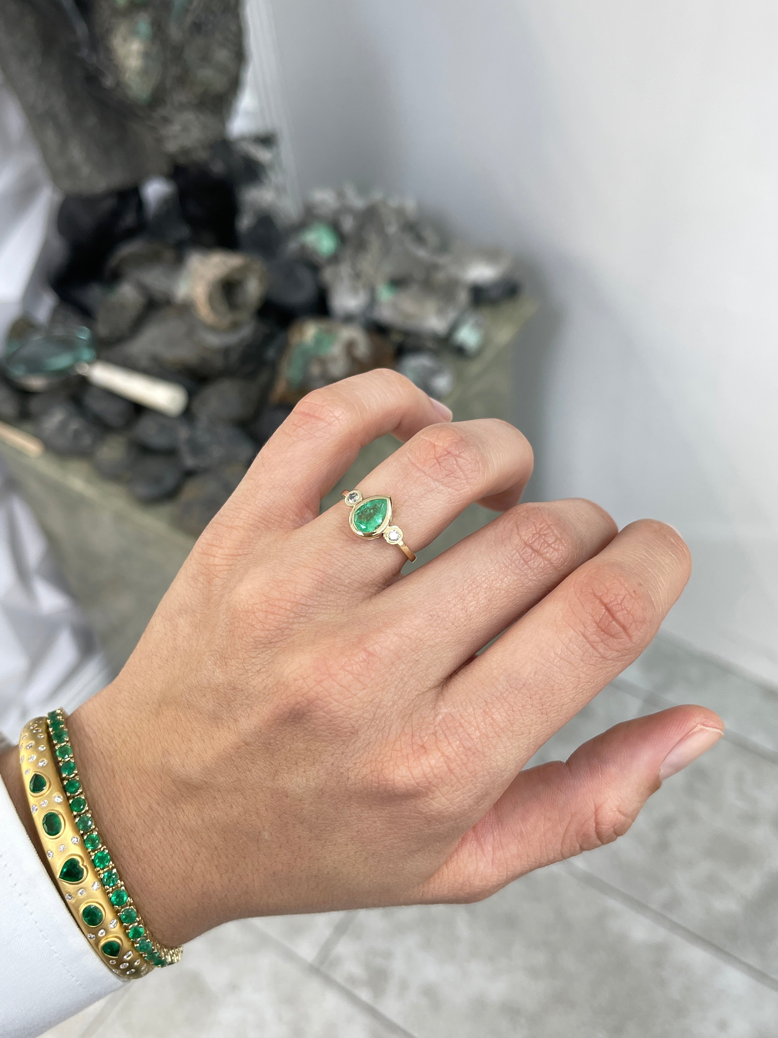 Bezel set tear drop emerald and diamond engagement ring in 14k gold, featuring a three-stone design by JR Colombian Emeralds.