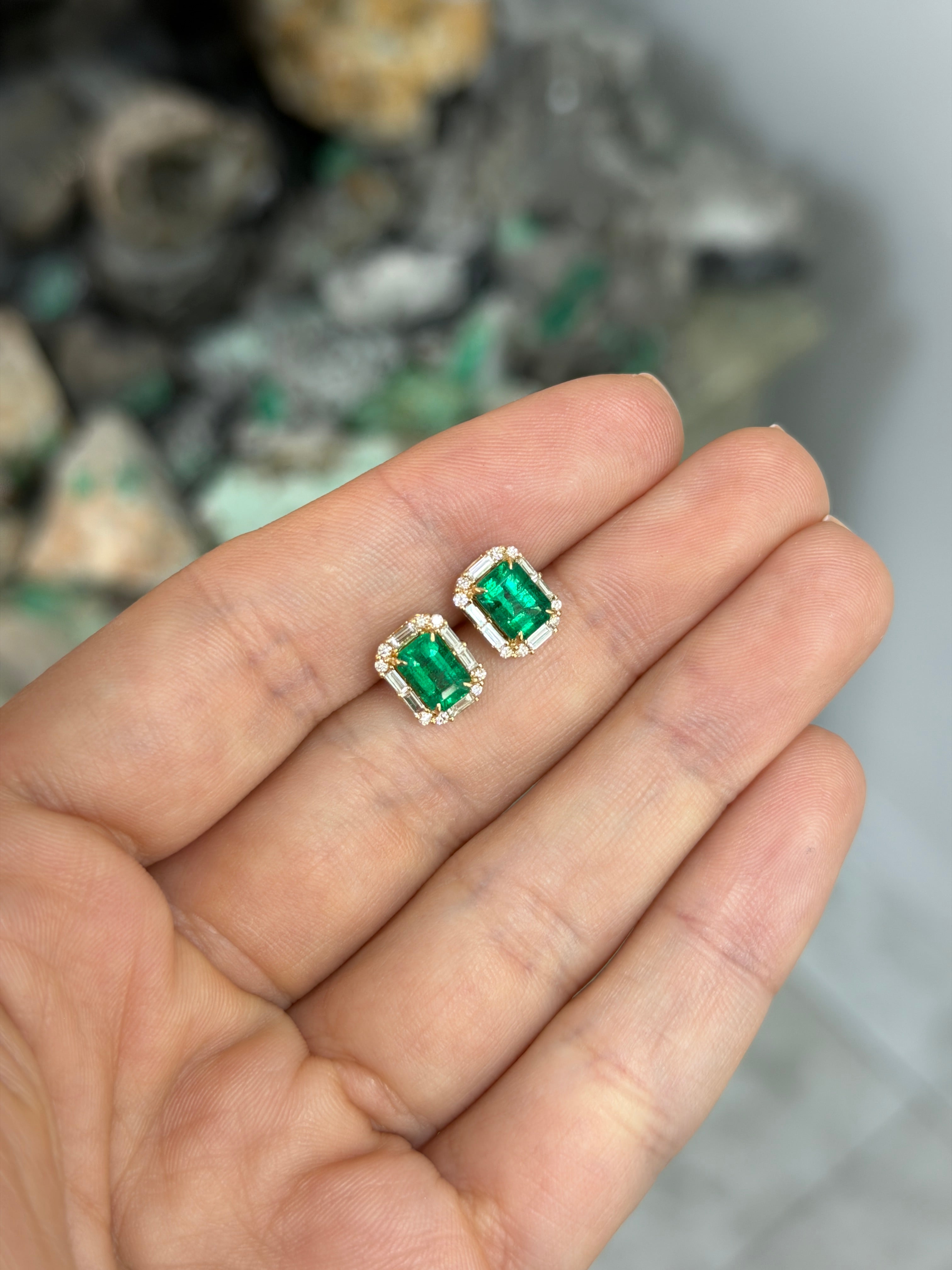 18K gold emerald and diamond halo stud earrings featuring rich green emeralds and baguette diamonds, detailed jewelry design.