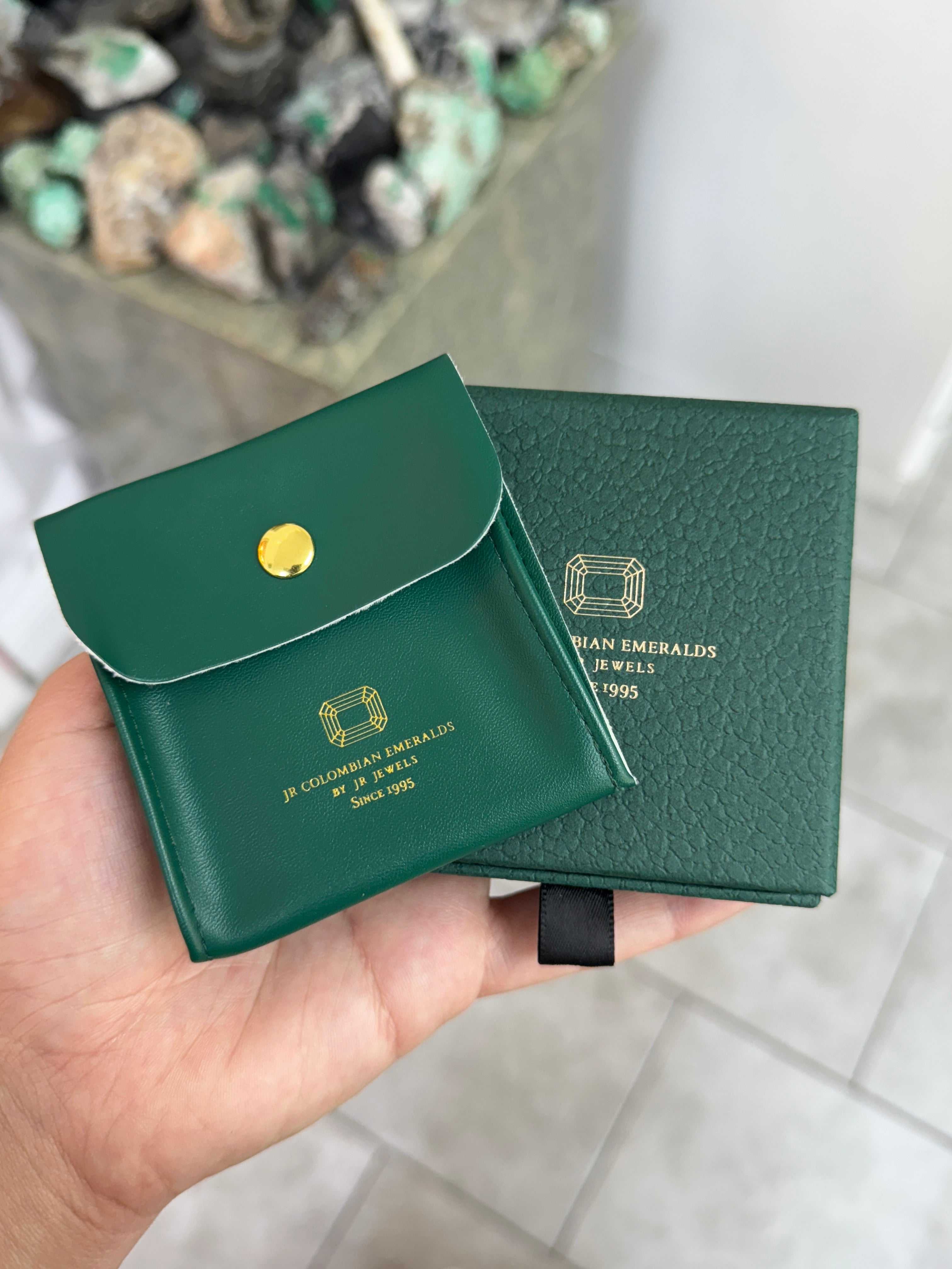 Emerald huggie earring by JR Colombian Emeralds featuring three-prong setting in 14K gold, close-up view of the jewelry.