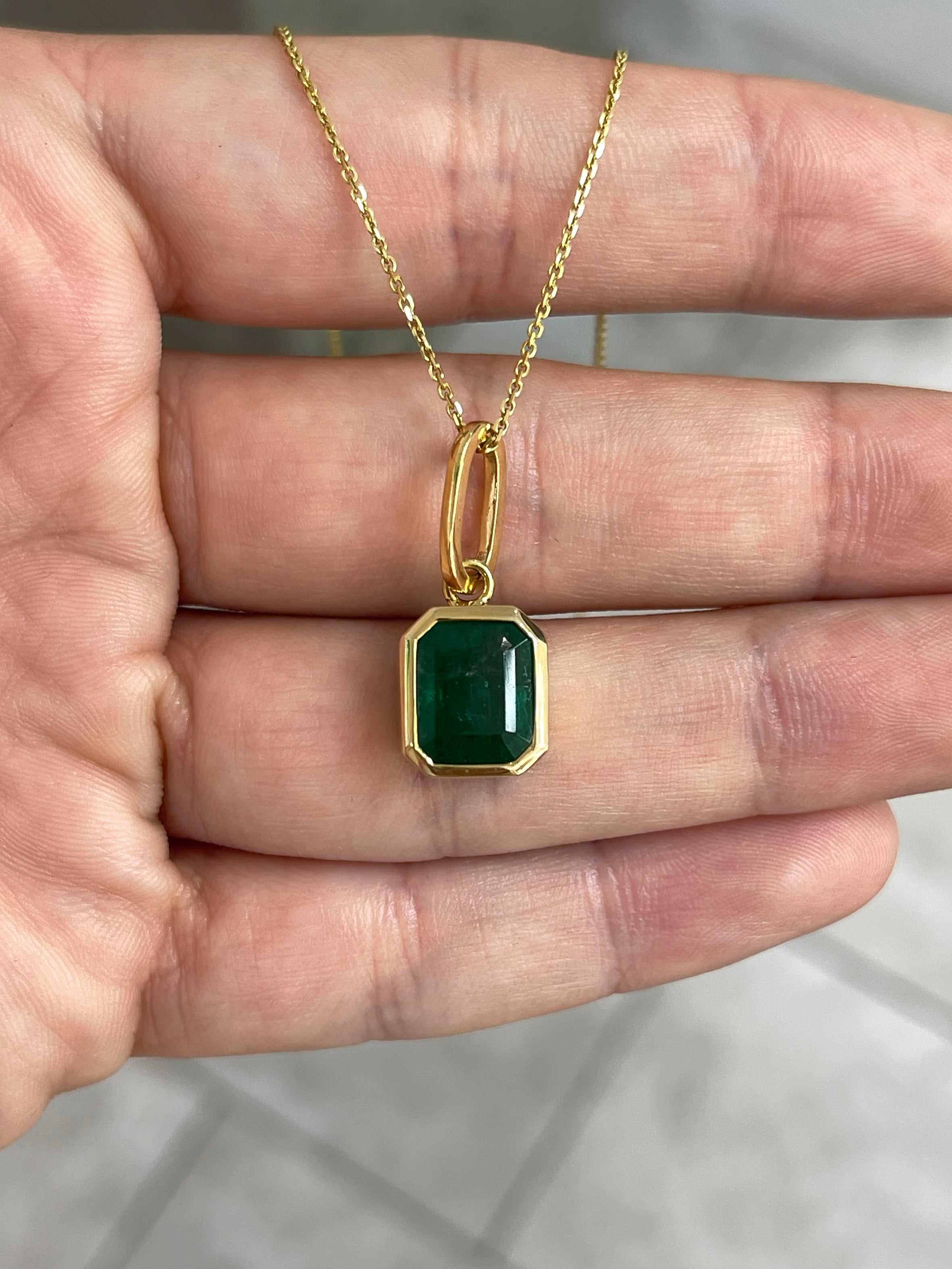 Dark green Zambian emerald necklace with 4.98 carat bezel-set emerald pendant in 14K gold, featuring intricate jewelry design.