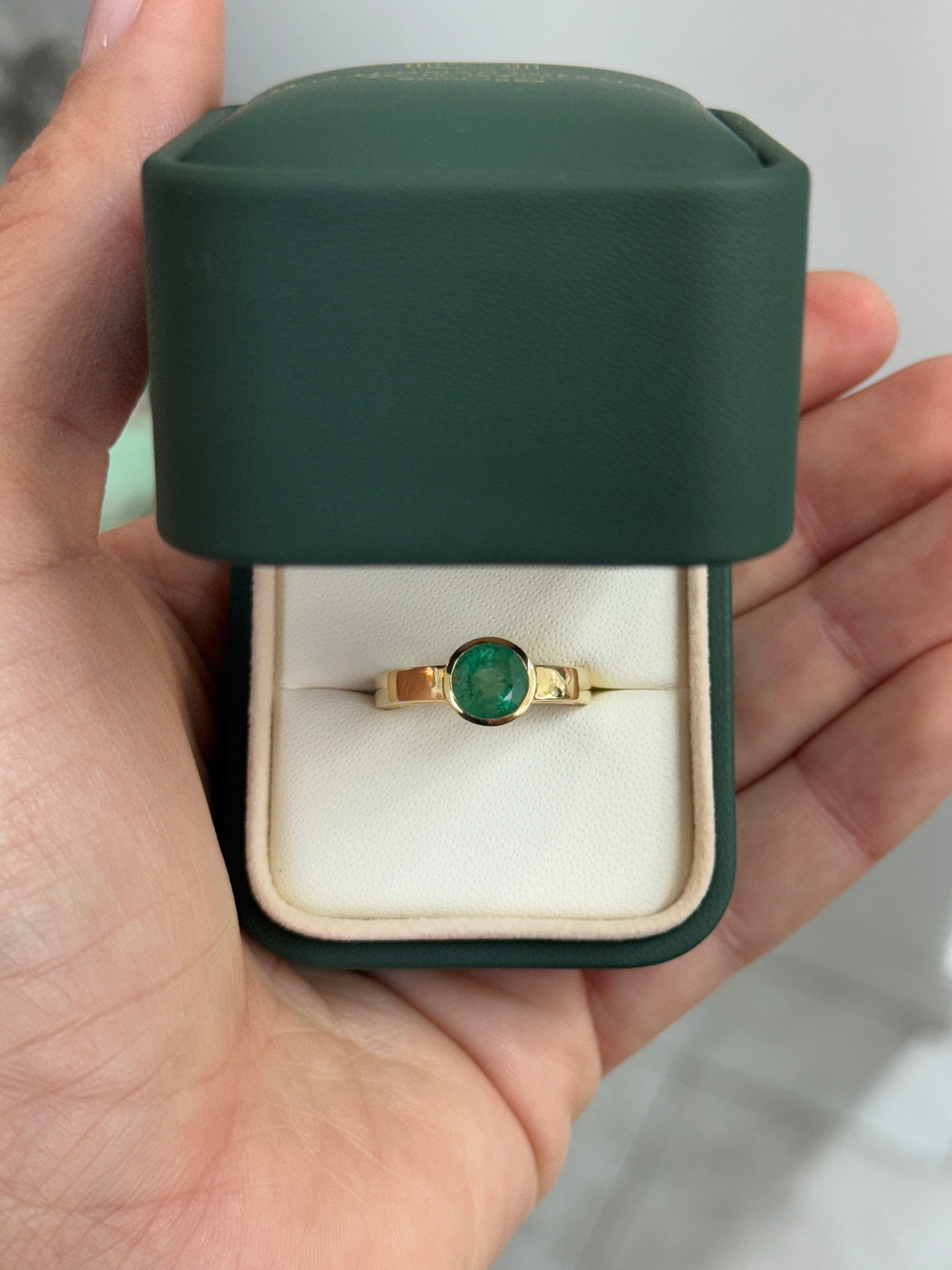 Bezel set 1.73 carat round emerald solitaire ring in 14K gold by JR Colombian Emeralds, showcasing the vibrant green gemstone.