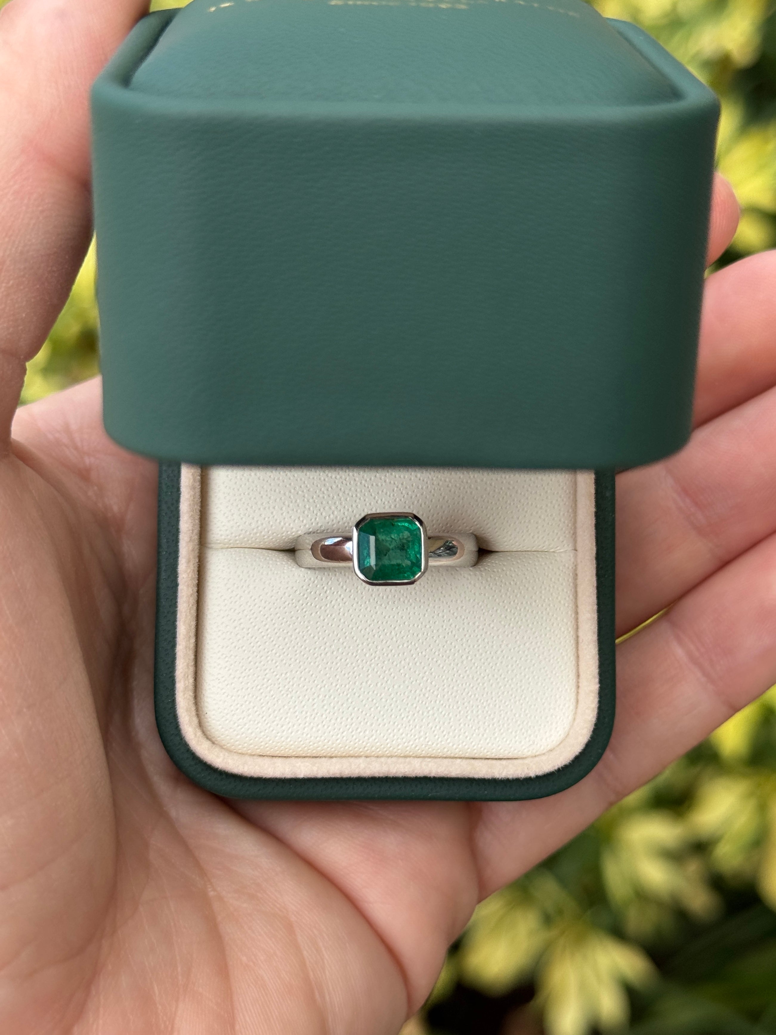 1.32 carat Asscher cut emerald solitaire ring in white gold bezel setting by JR Colombian Emeralds, showcasing a sparkling gemstone.