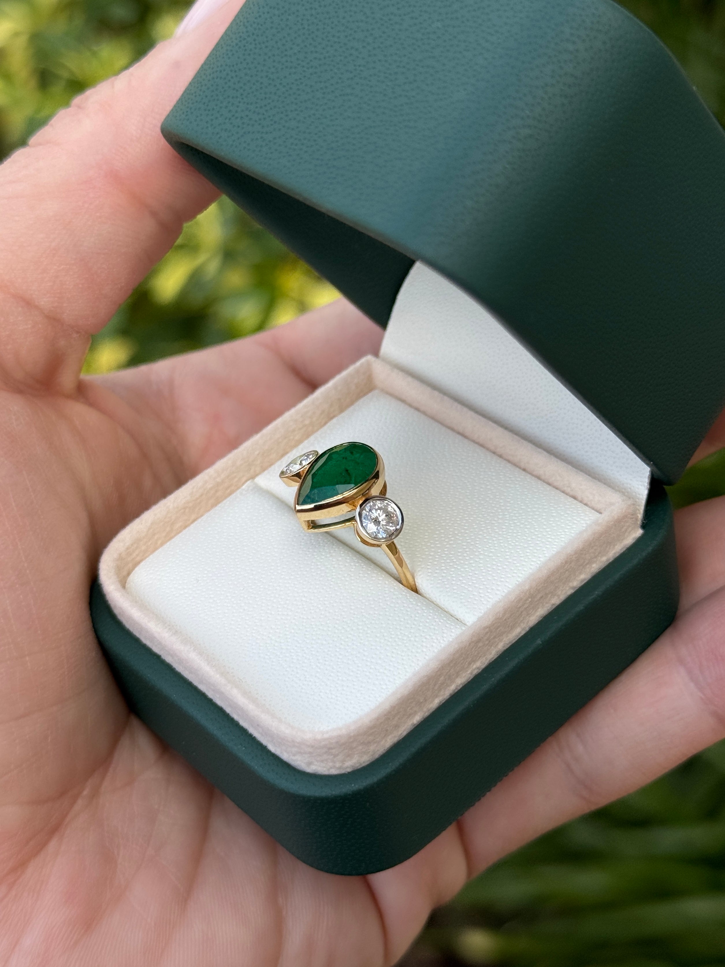 Pear-shaped emerald three-stone ring with round diamonds, bezel setting, 18K yellow gold, by JR Colombian Emeralds.