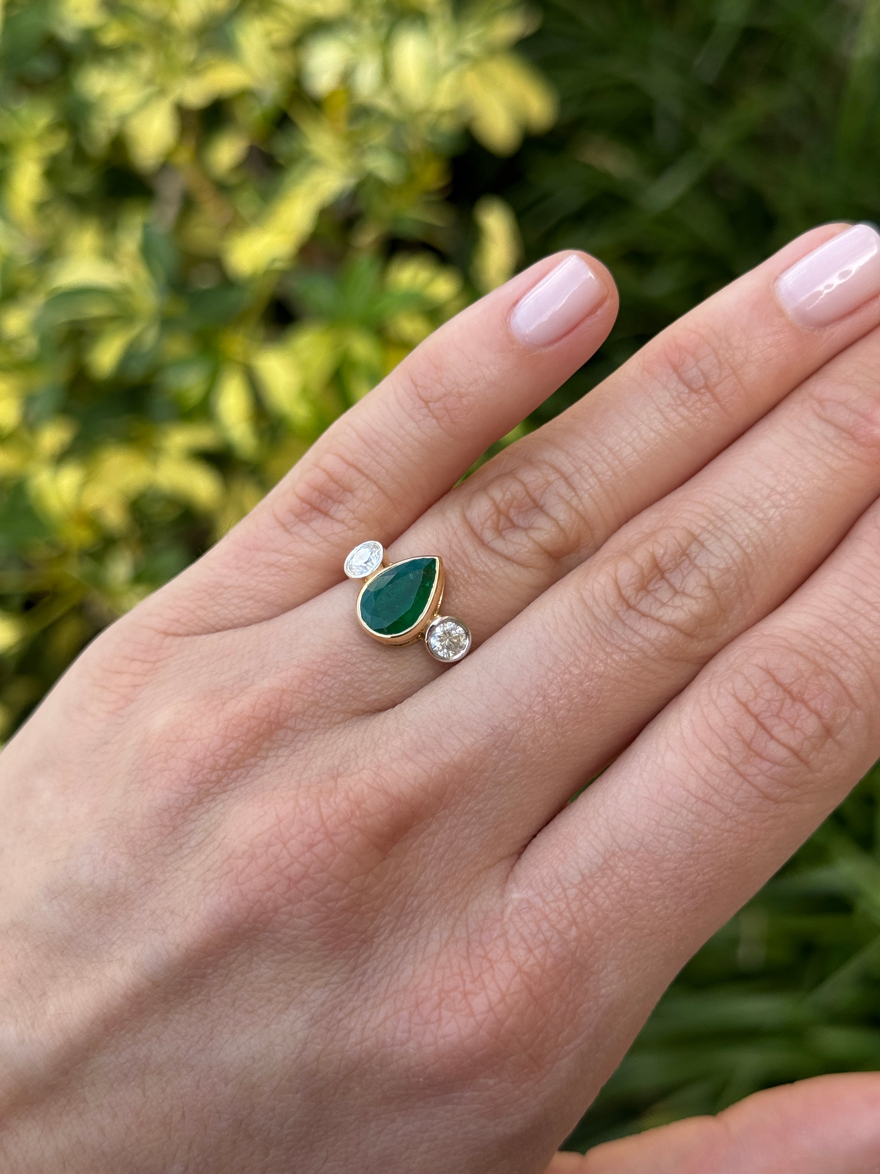Pear-shaped emerald three-stone ring with round diamond accents in 18K yellow gold by JR Colombian Emeralds.