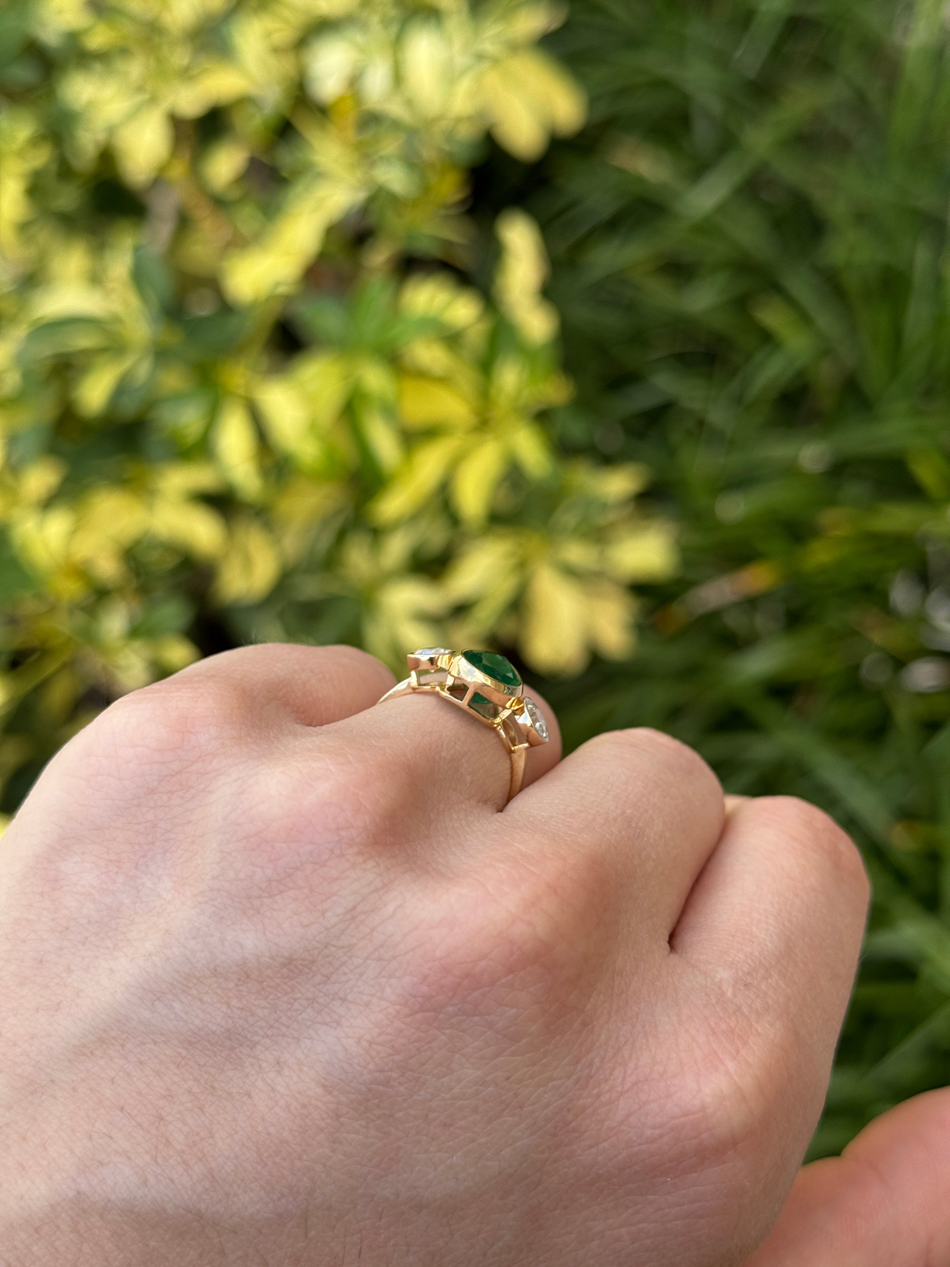 Pear-shaped emerald three-stone ring with round diamond accents in 18K yellow gold, designed by JR Colombian Emeralds.