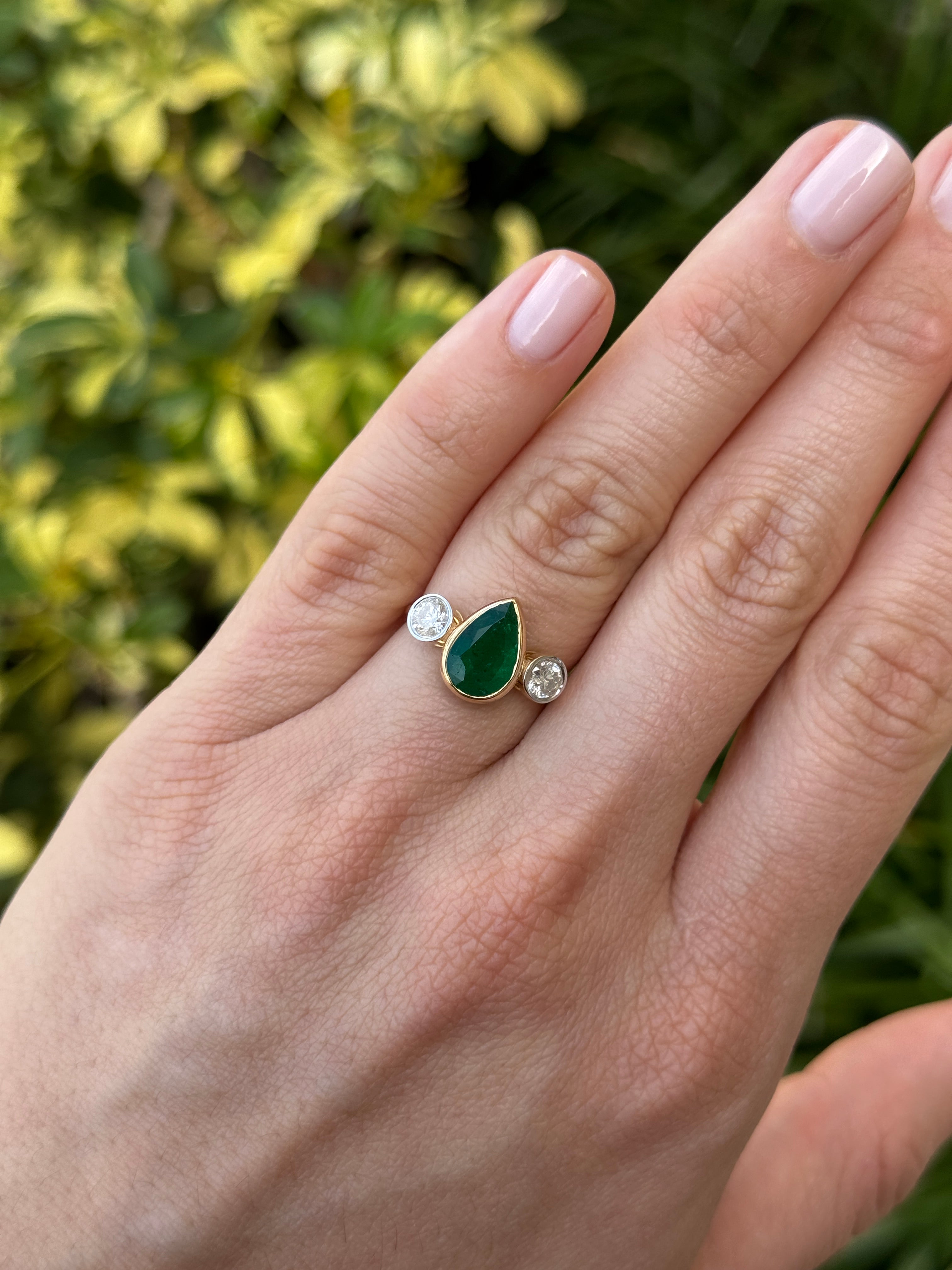Pear-shaped emerald three-stone ring with round diamond accents in 18K yellow gold, by JR Colombian Emeralds.