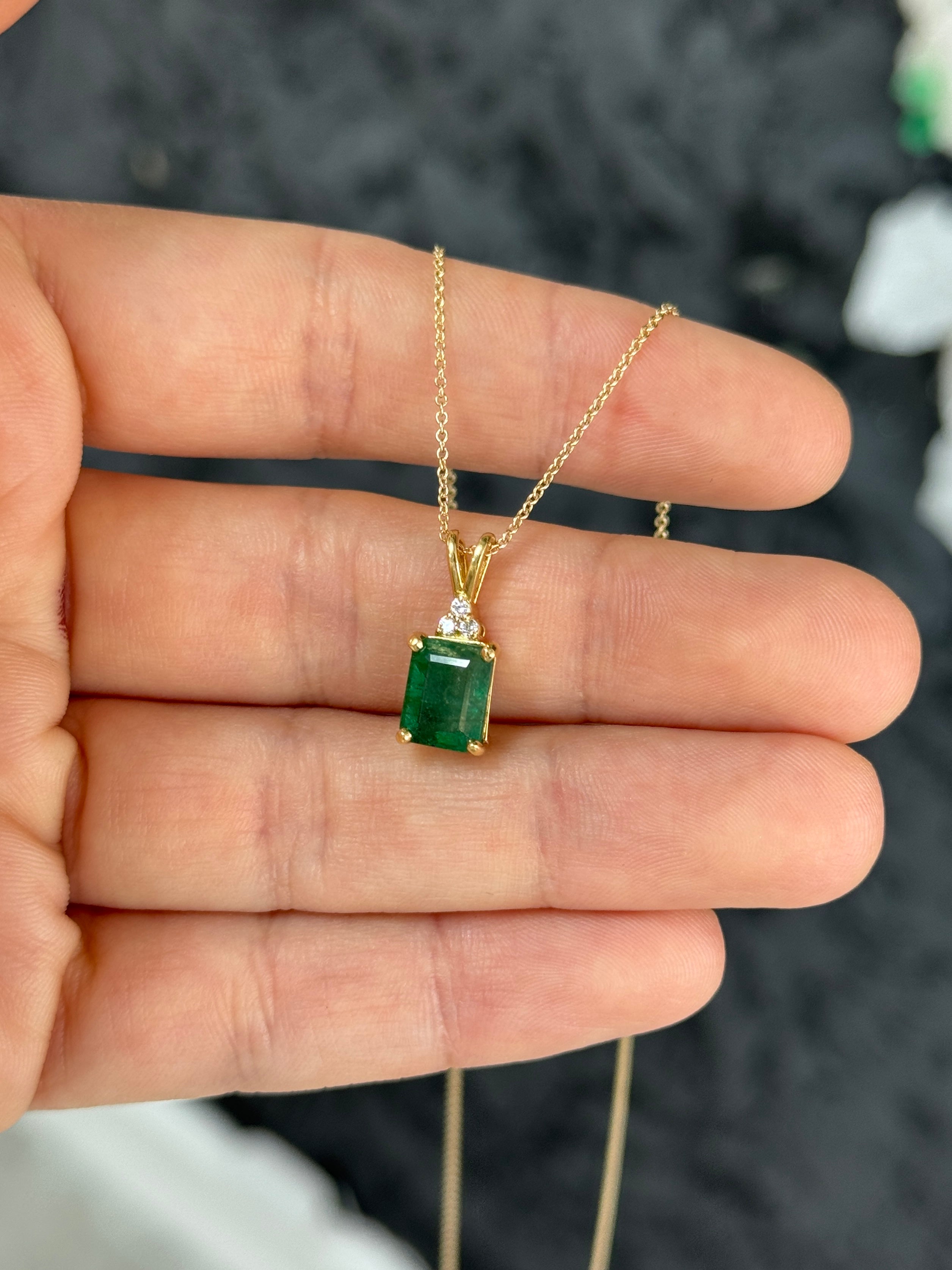 Emerald cut emerald pendant with trefoil diamond accents in 14K gold, showcasing a beautiful green gemstone and elegant design.