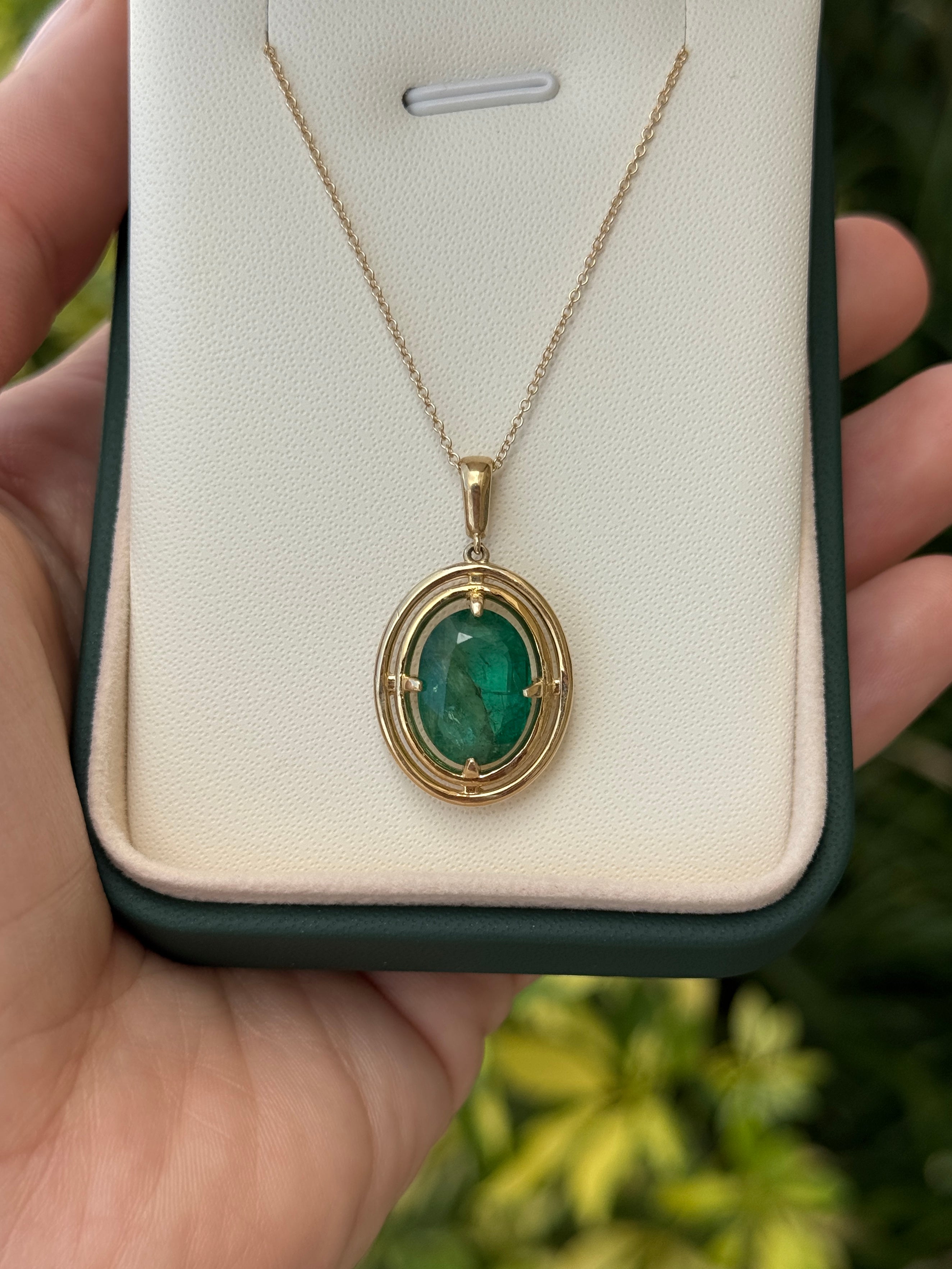 Ciondolo solitario con smeraldo ovale e doppia cornice a corona in oro giallo 14 carati, con montatura flottante a quattro griffe realizzata da JR Colombian Emeralds.