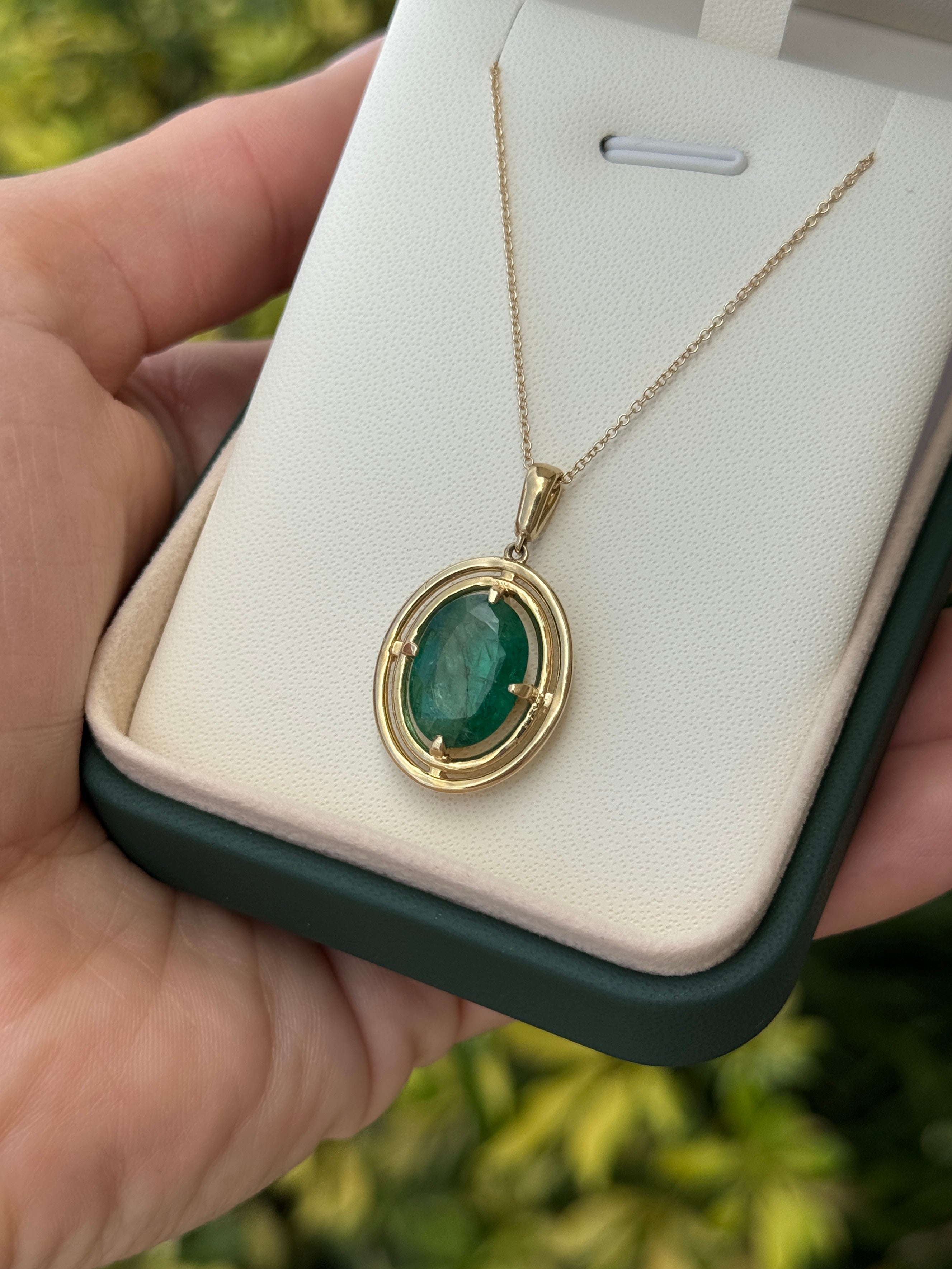 Ciondolo con smeraldo ovale e doppio castone a corona in oro giallo 14 carati, caratterizzato da una montatura flottante a quattro griffe e da uno smeraldo brillante da 5,71 carati.
