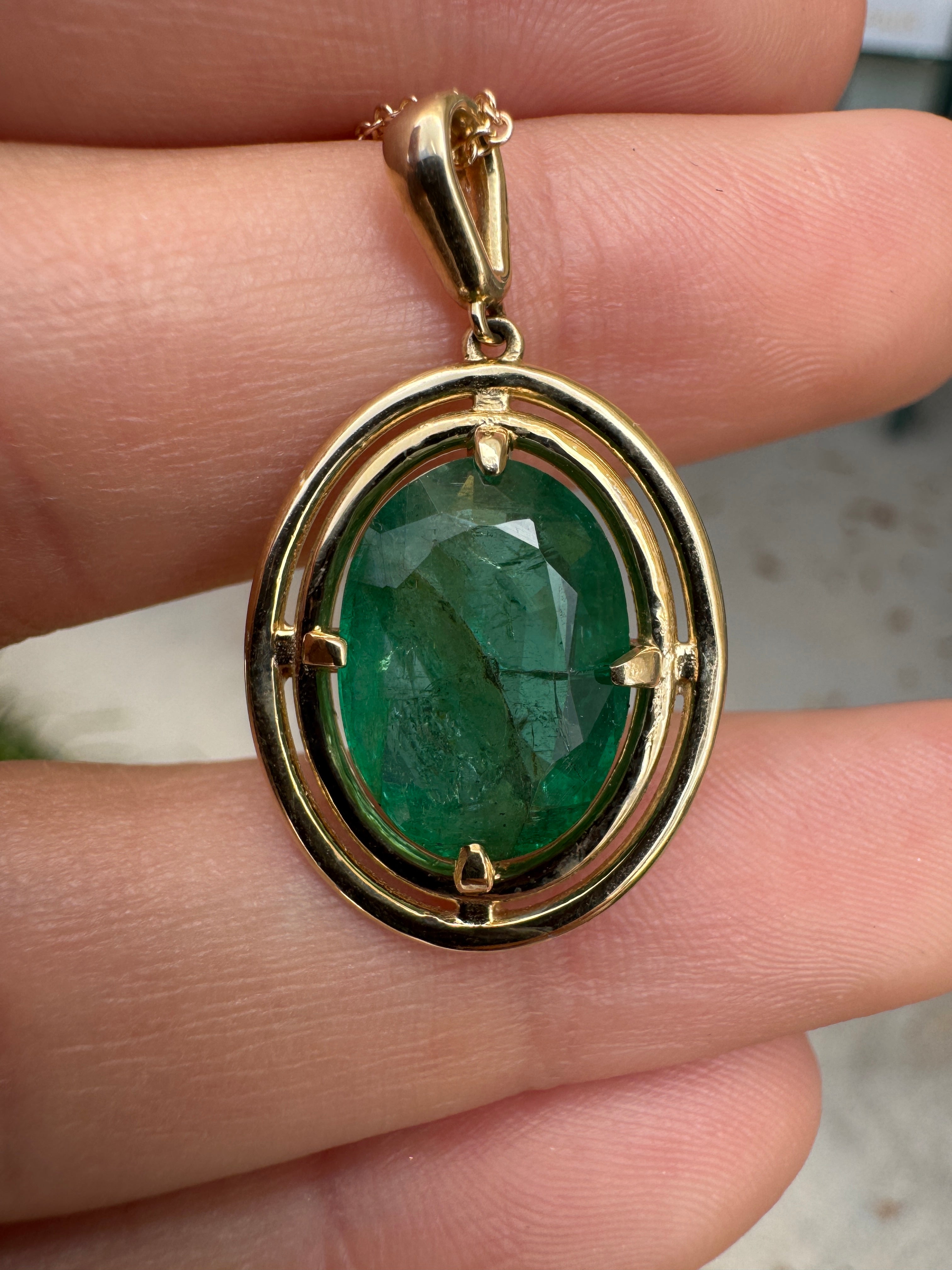 Ciondolo solitario con smeraldo ovale e doppio halo in oro giallo 14 carati, con montatura flottante a quattro griffe e 5,71 carati.