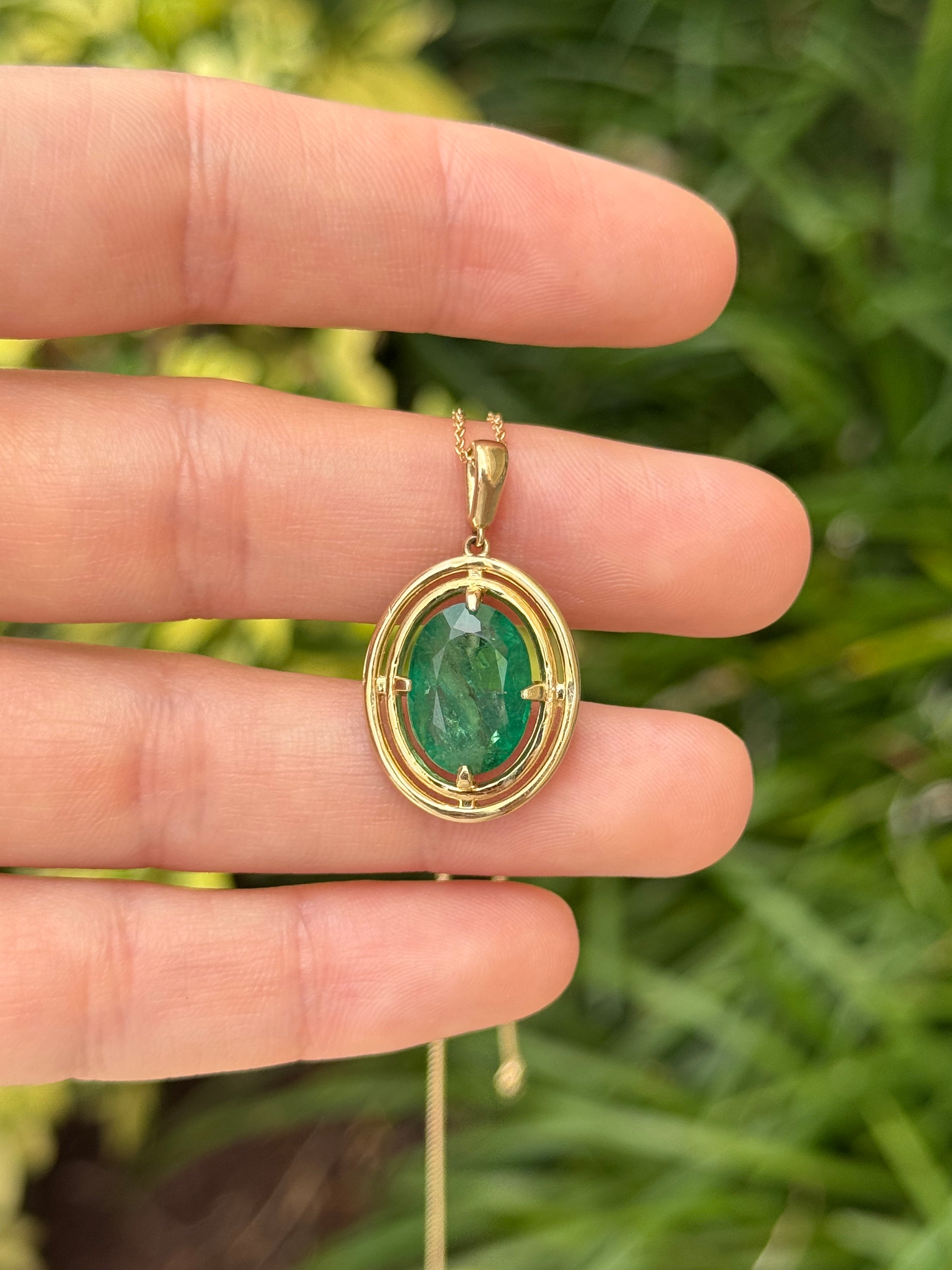 Ciondolo solitario con smeraldo ovale da 5,71 carati, con doppia cornice a corona in oro giallo 14 carati, caratterizzato da una montatura flottante a quattro griffe.