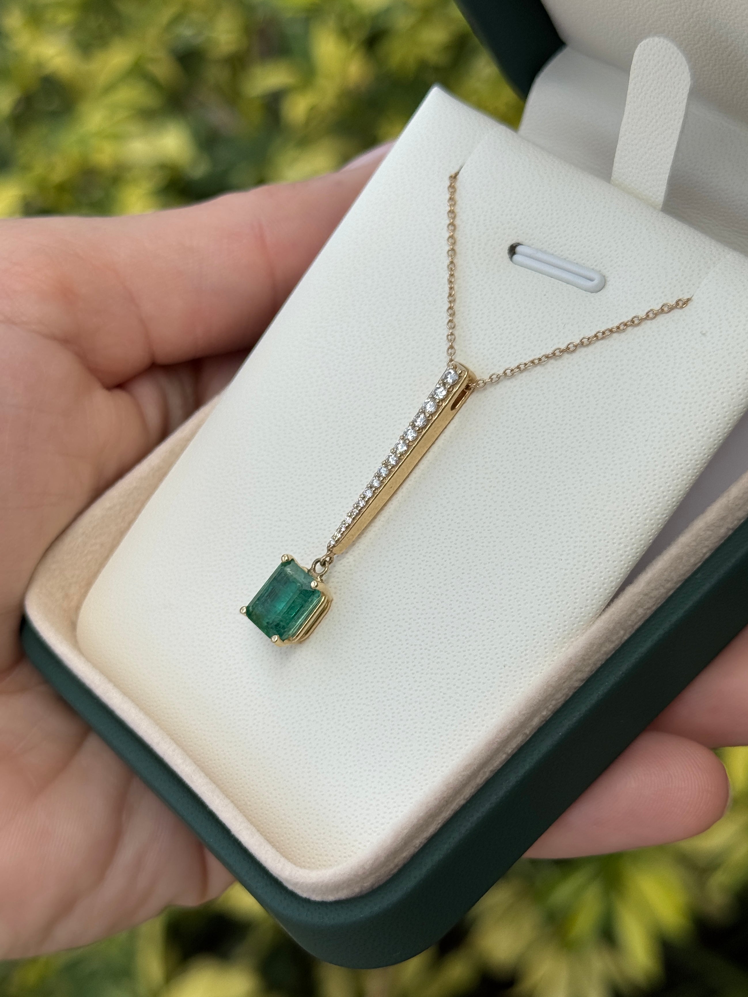 14K gold emerald cut emerald and diamond pendant necklace with V-drop design and diamond accents, featuring natural green emeralds.