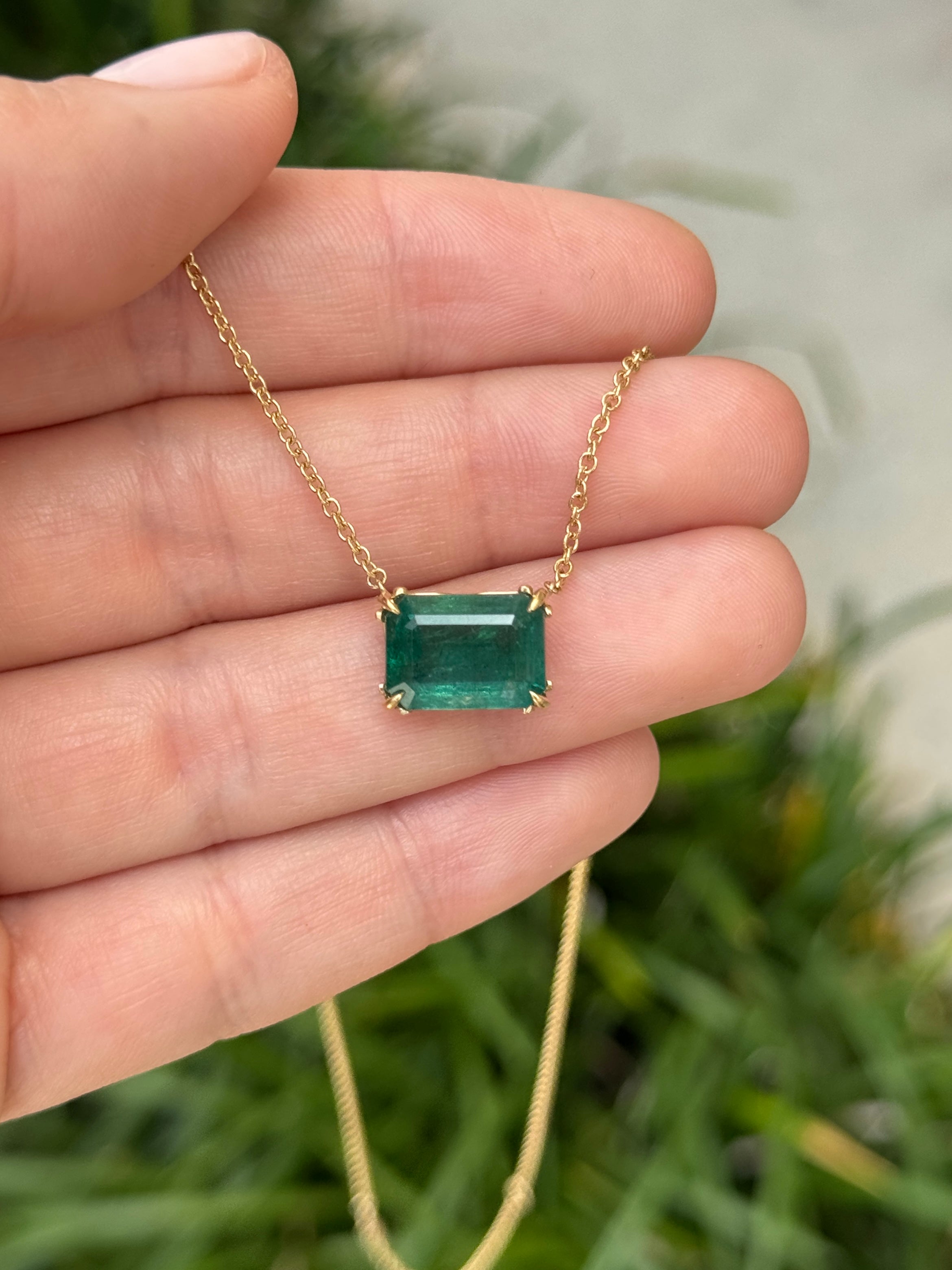 18K gold emerald solitaire necklace with east-to-west station design and fleur de lis accents by JR Colombian Emeralds