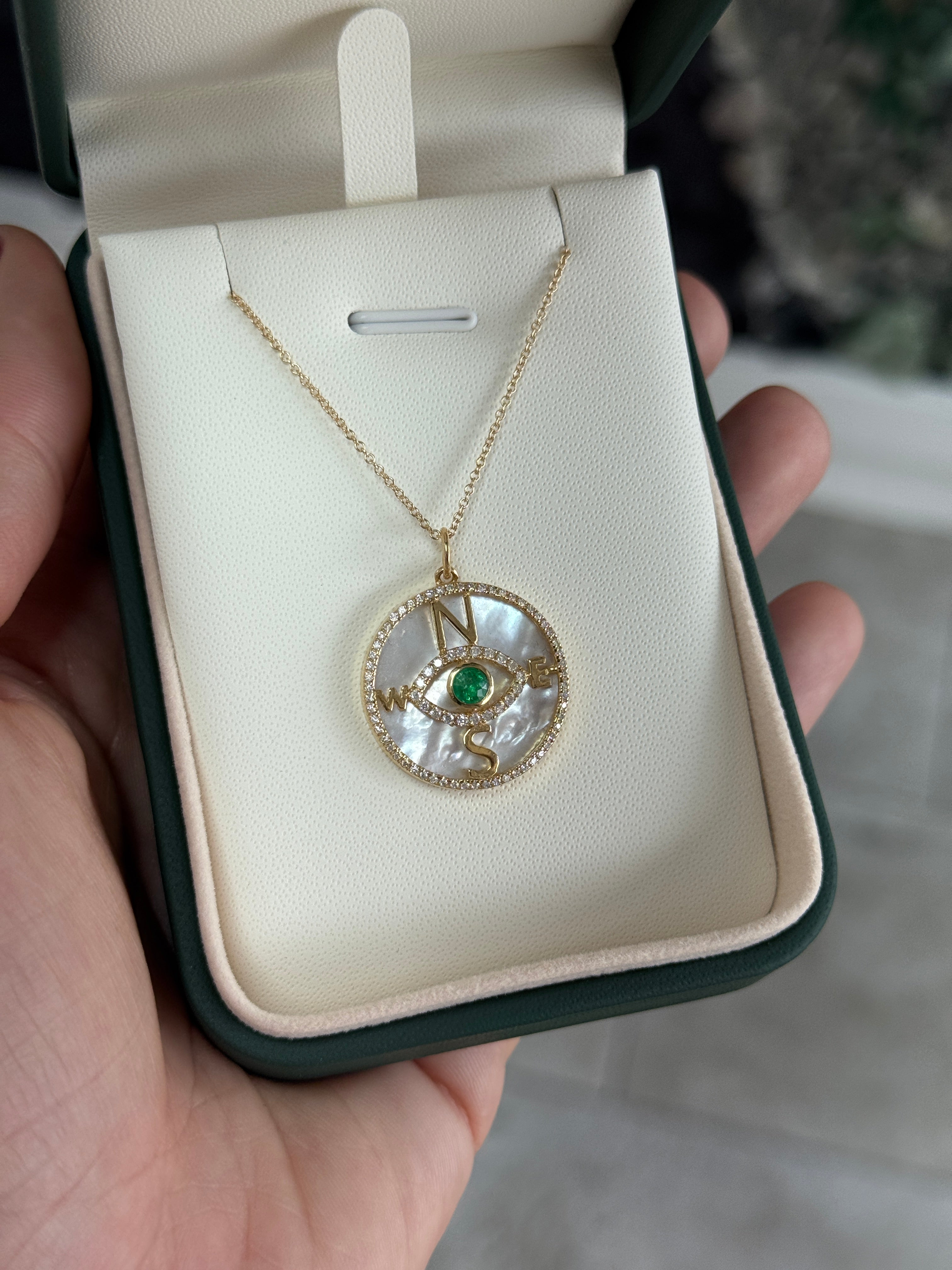14K gold emerald and diamond compass evil eye pendant necklace with mother of pearl, featuring round emeralds and intricate design.