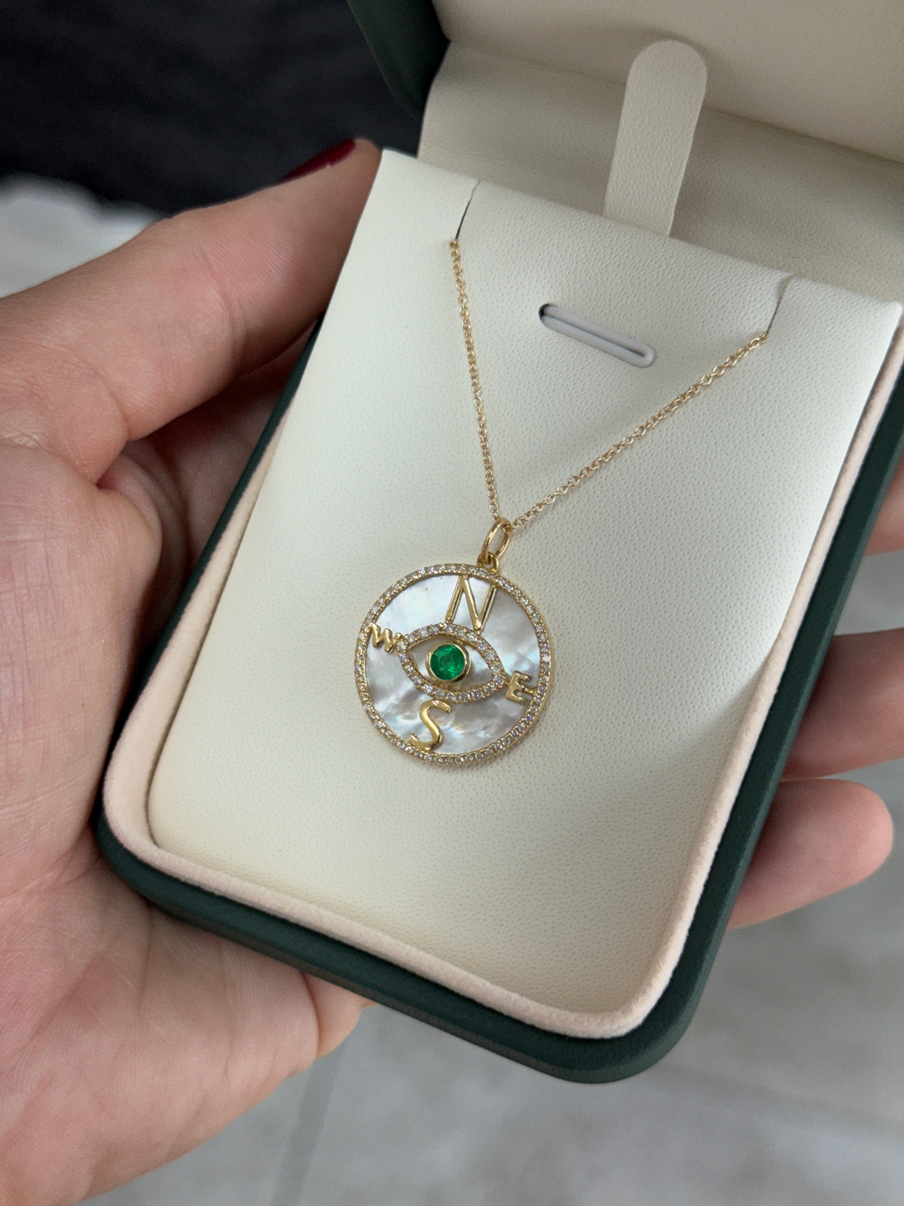 14K gold emerald and diamond compass evil eye pendant necklace with mother of pearl, featuring natural round emeralds and intricate design.