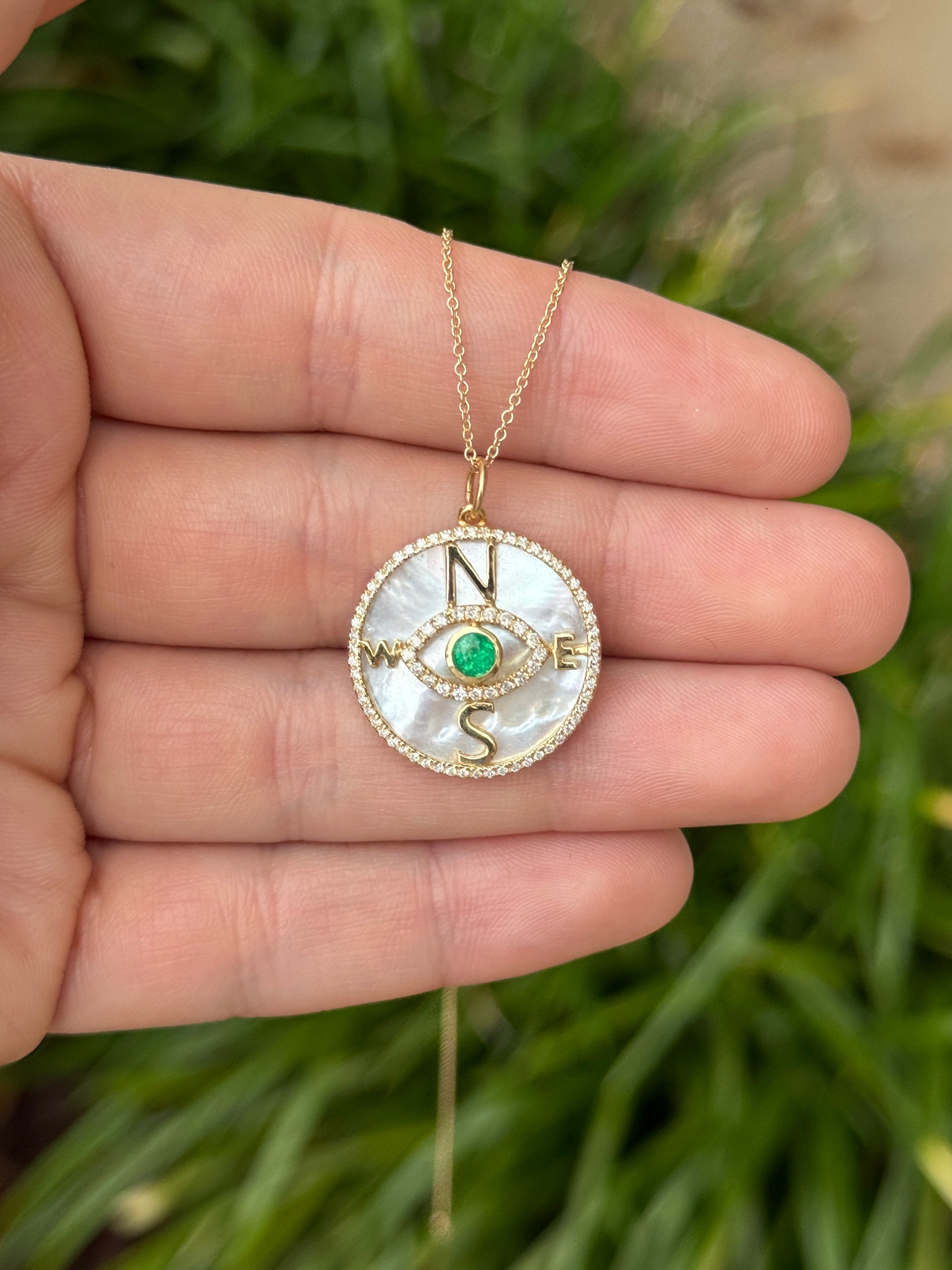 14K gold Emerald and diamond mother of pearl compass evil eye pendant necklace with 9.17tcw, featuring round emeralds and intricate details.