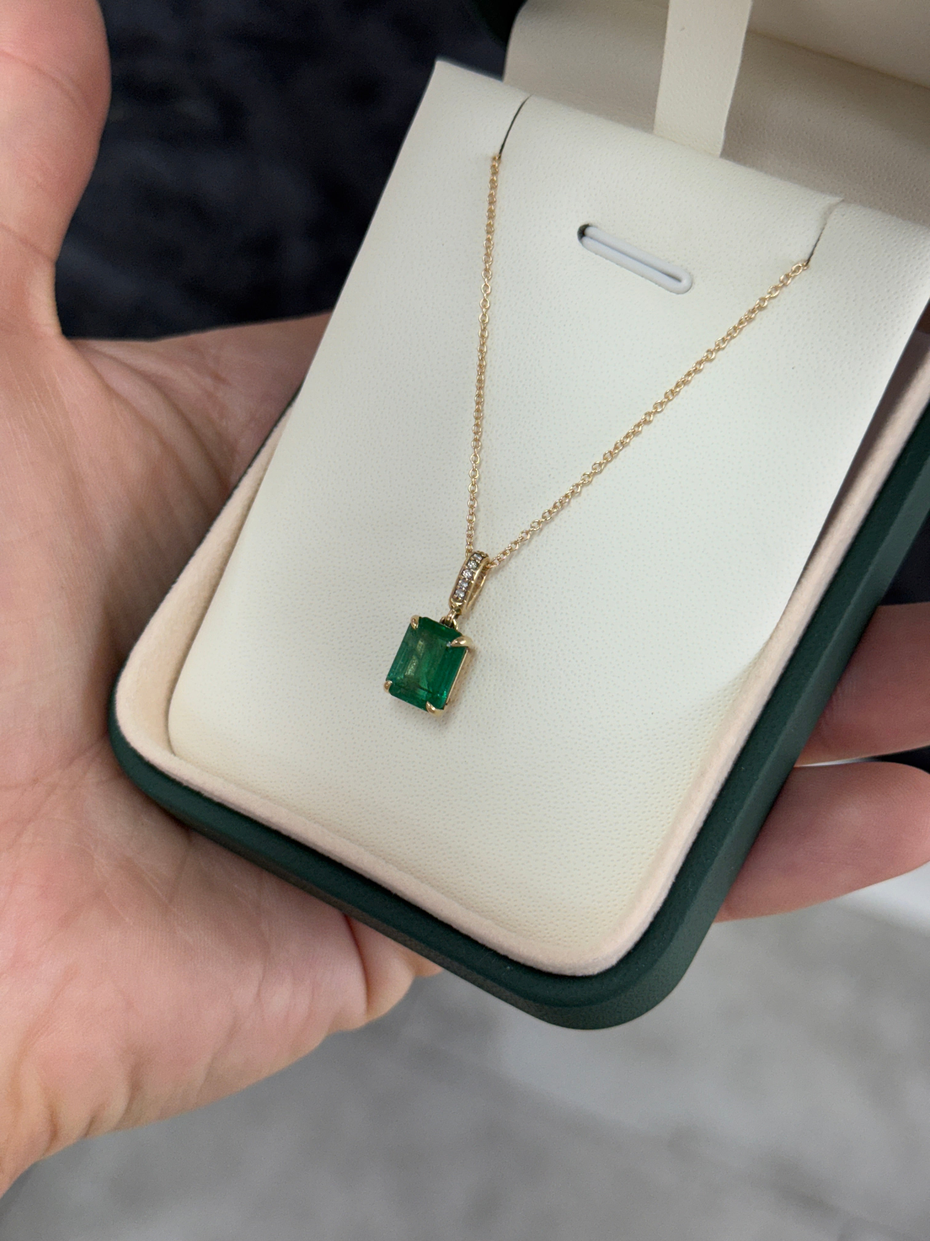 Emerald cut emerald pendant with diamond bail in 14K gold, showcasing a vibrant green gemstone and elegant jewelry design.