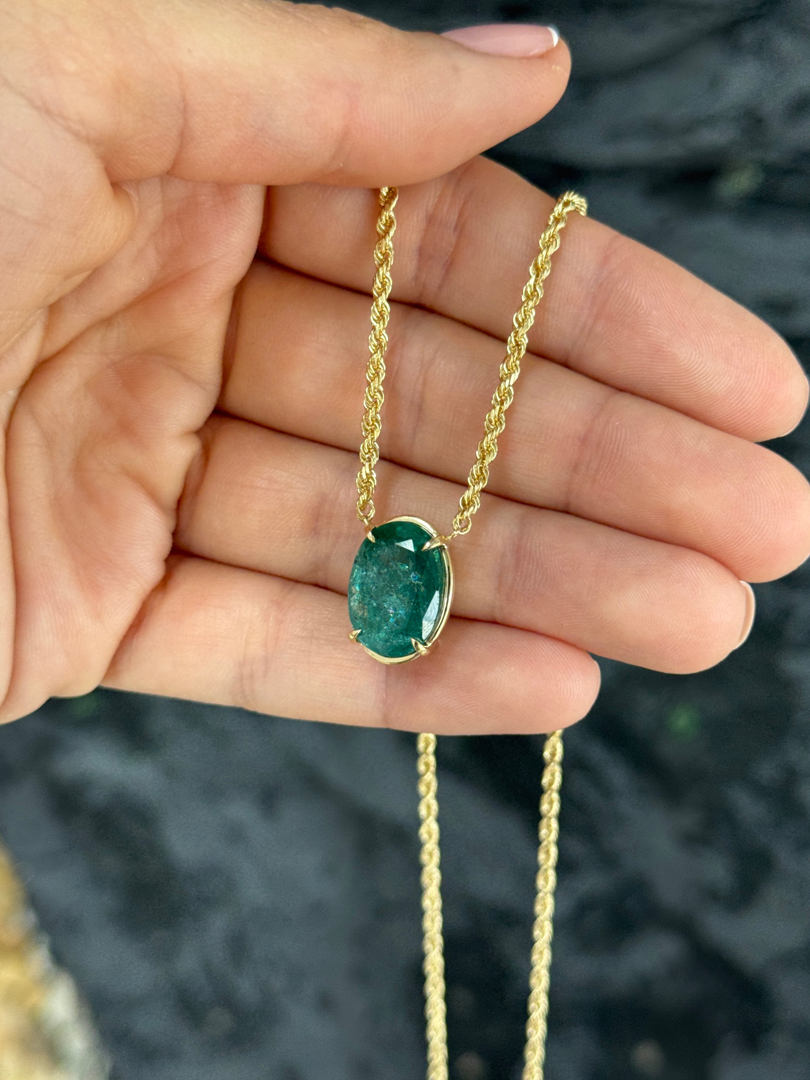 9 carat oval emerald solitaire necklace in yellow gold, featuring a vivid green emerald pendant on a 14K chain.