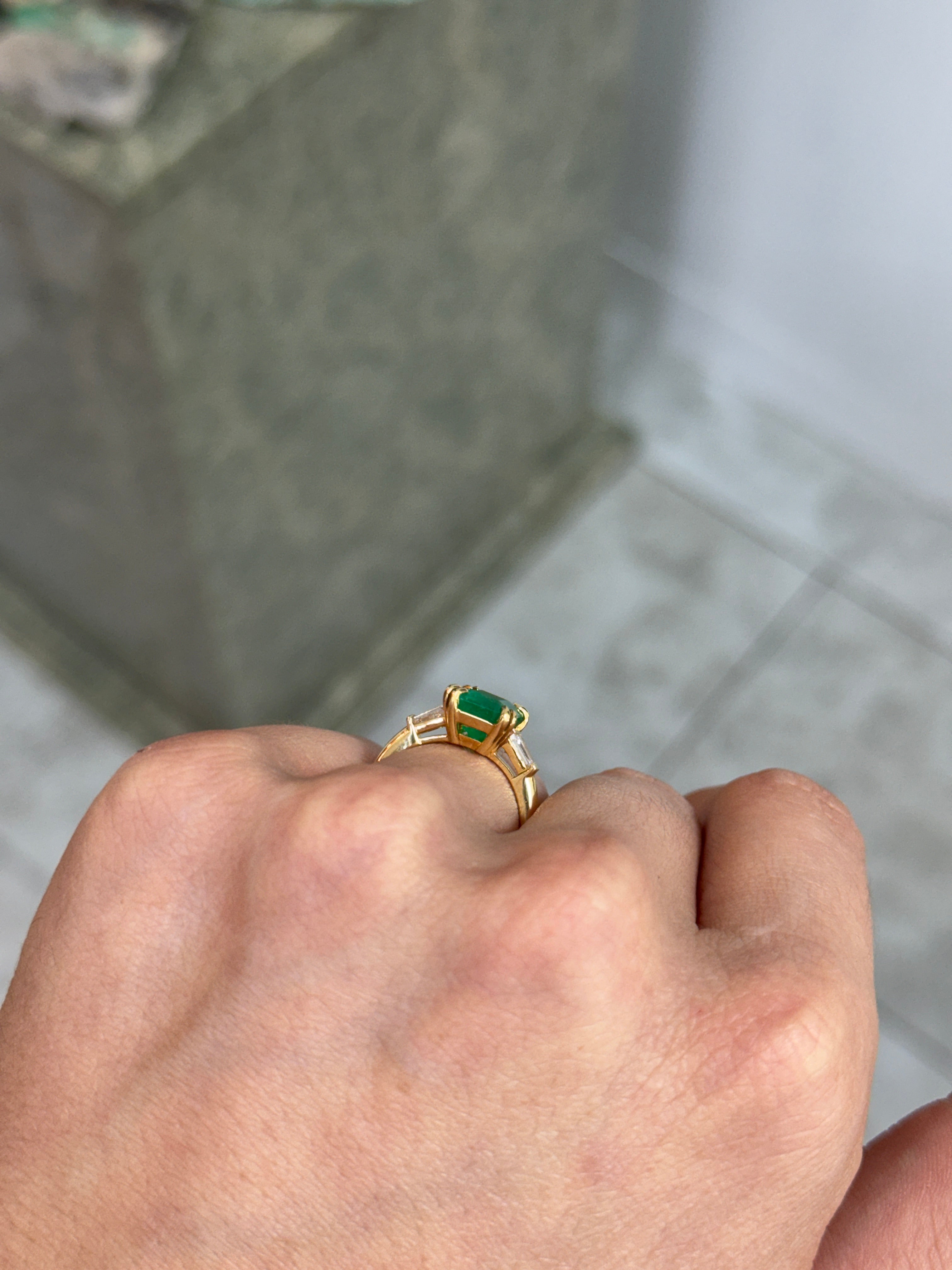 18K Colombian emerald and tapered baguette diamond ring showcasing vibrant green emeralds and sparkling diamonds in a fine jewelry design.