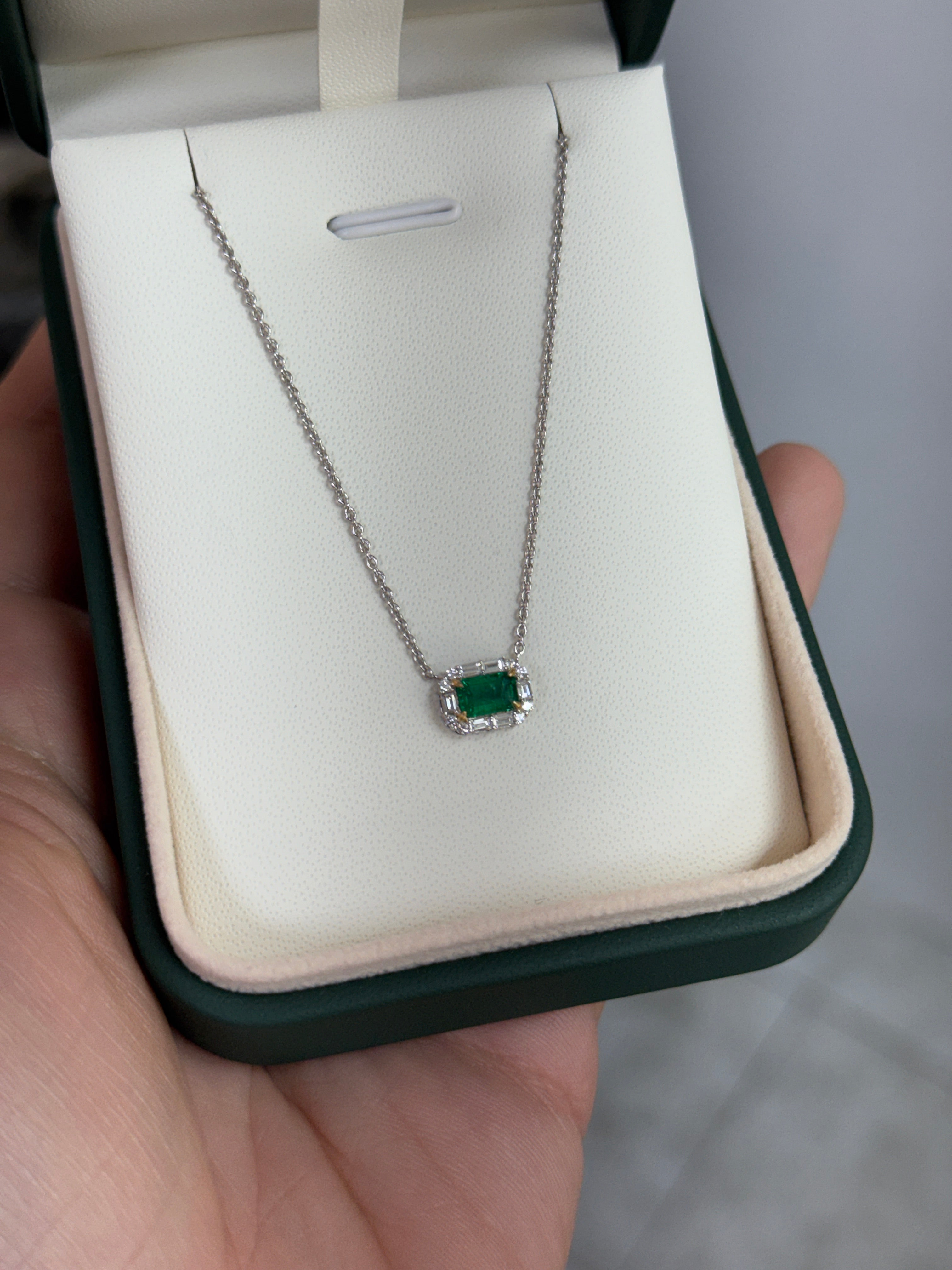 AAA+ natural emerald and baguette diamond halo necklace by JR Colombian Emeralds, featuring an east-to-west station design in 18K gold.