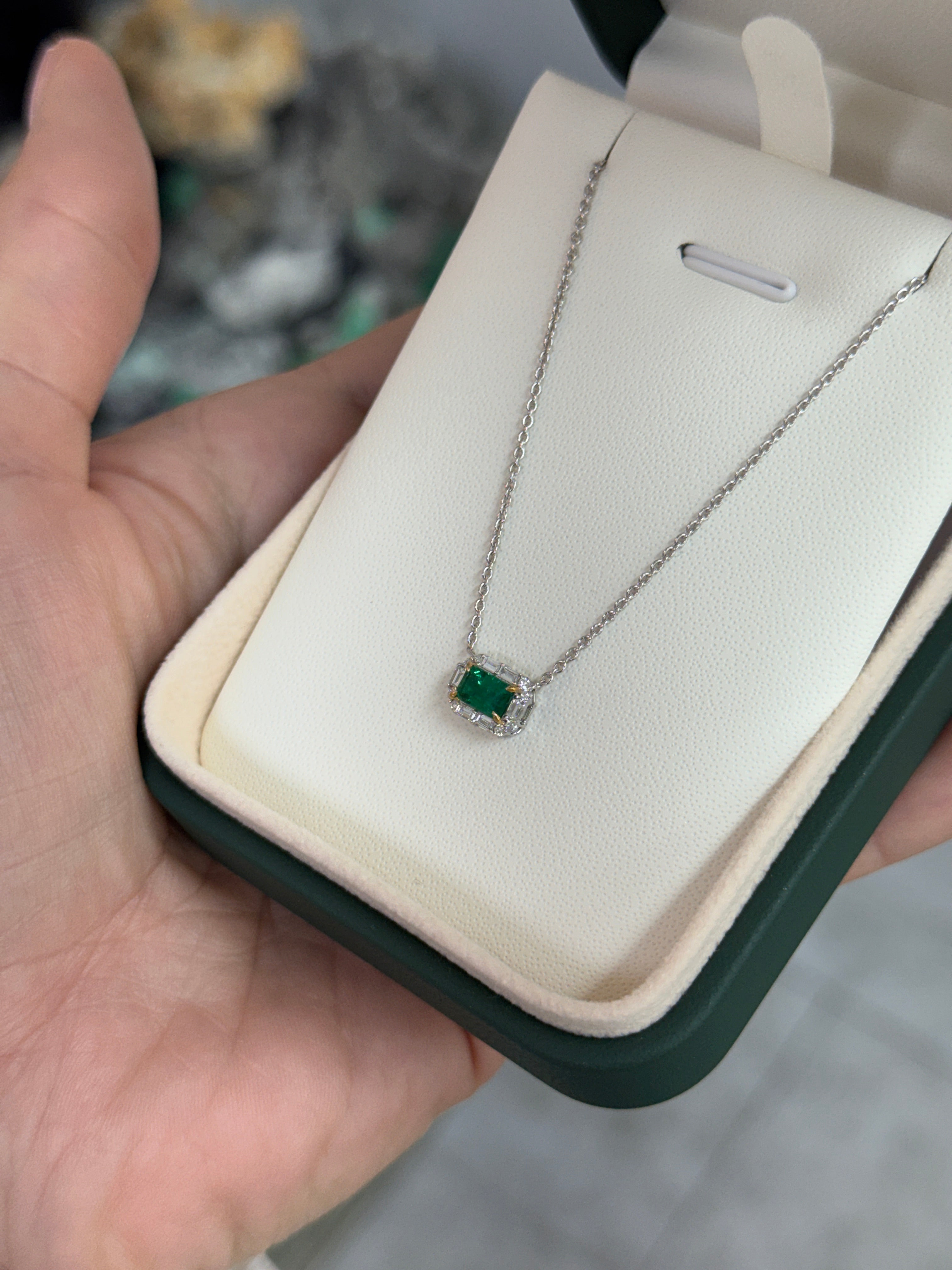 AAA+ natural emerald and baguette diamond halo necklace by JR Colombian Emeralds, showcasing an 18K gold east-to-west station design.
