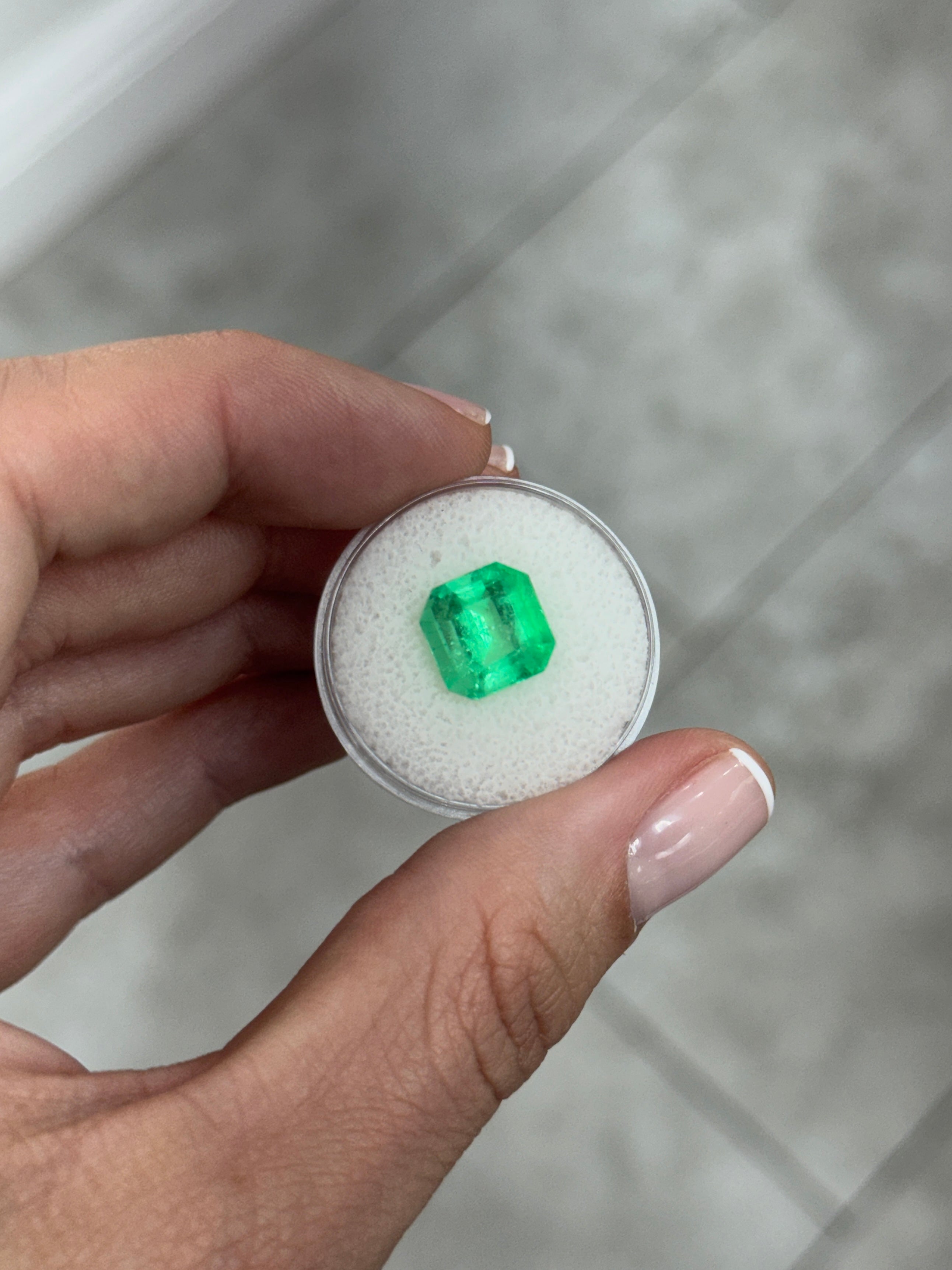 Loose 4.57 carat Colombian emerald Asscher cut with clipped corners, glowing vibrant green gemstone from JR Colombian Emeralds.