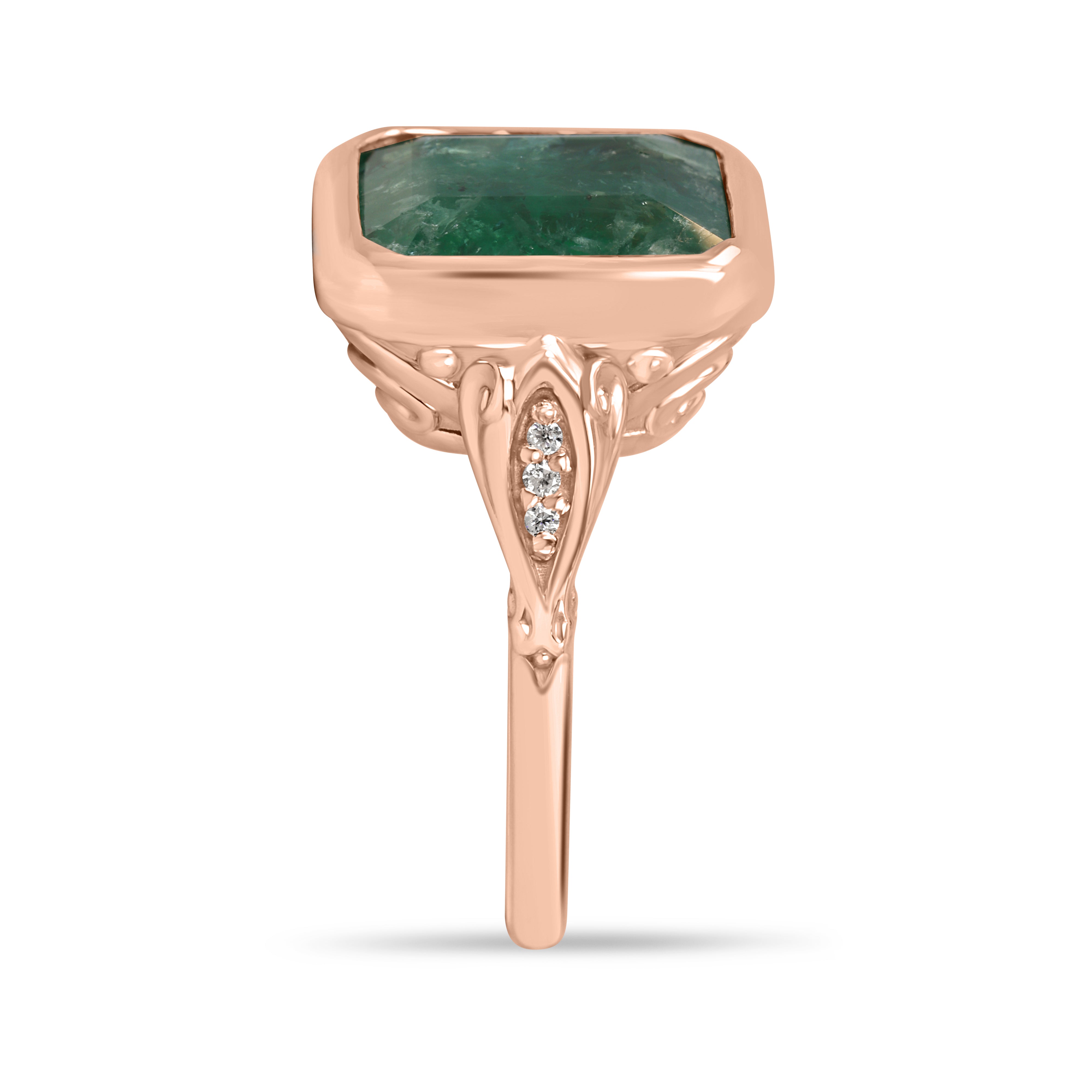 Vintage-inspired 14K rose gold emerald bezel ring with diamond shank and scroll basket detail by JR Colombian Emeralds.