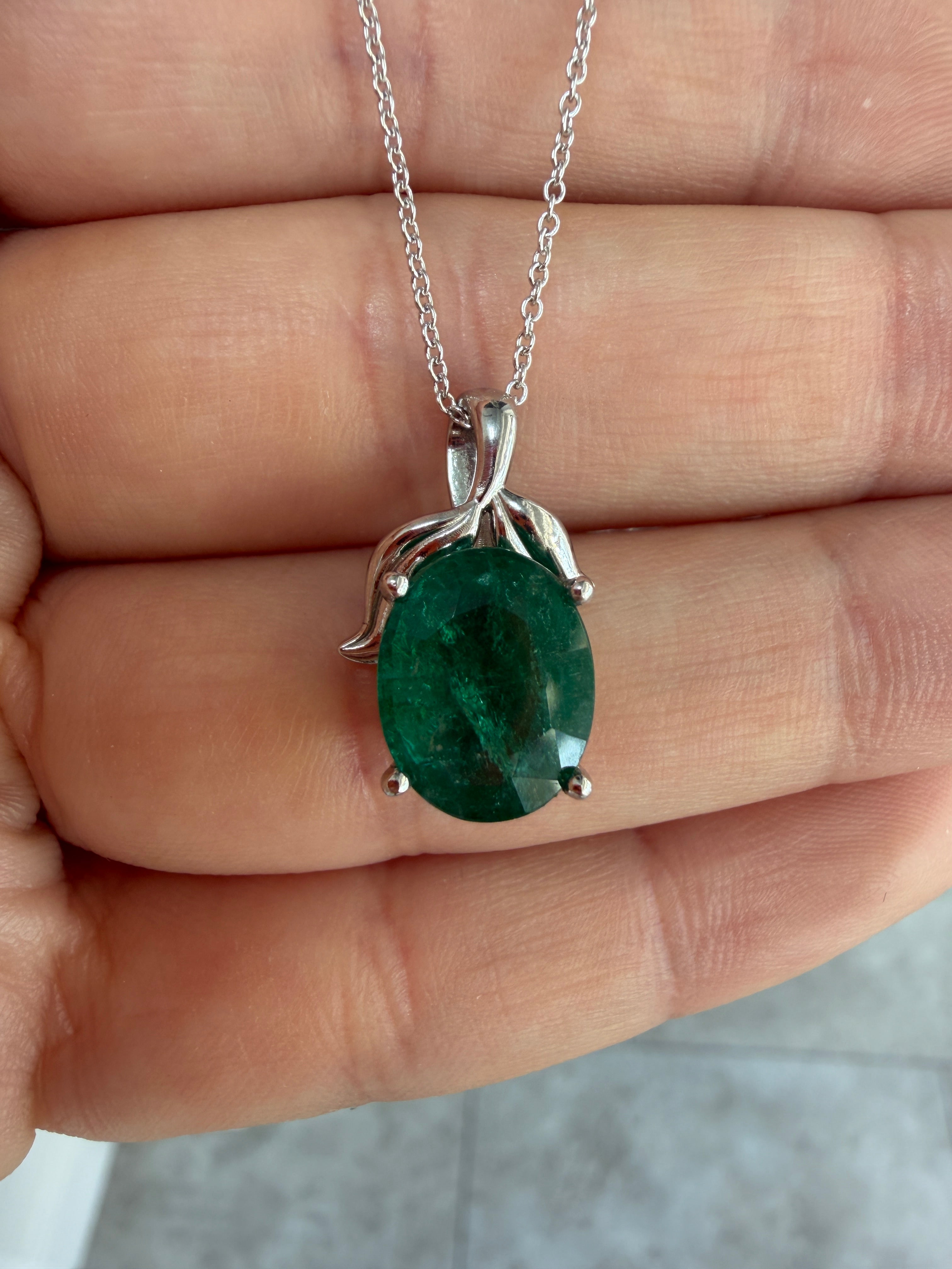 Emerald necklace with 3.23 carat oval cut emerald pendant featuring a leaf bail, platinum setting, natural inspired design.