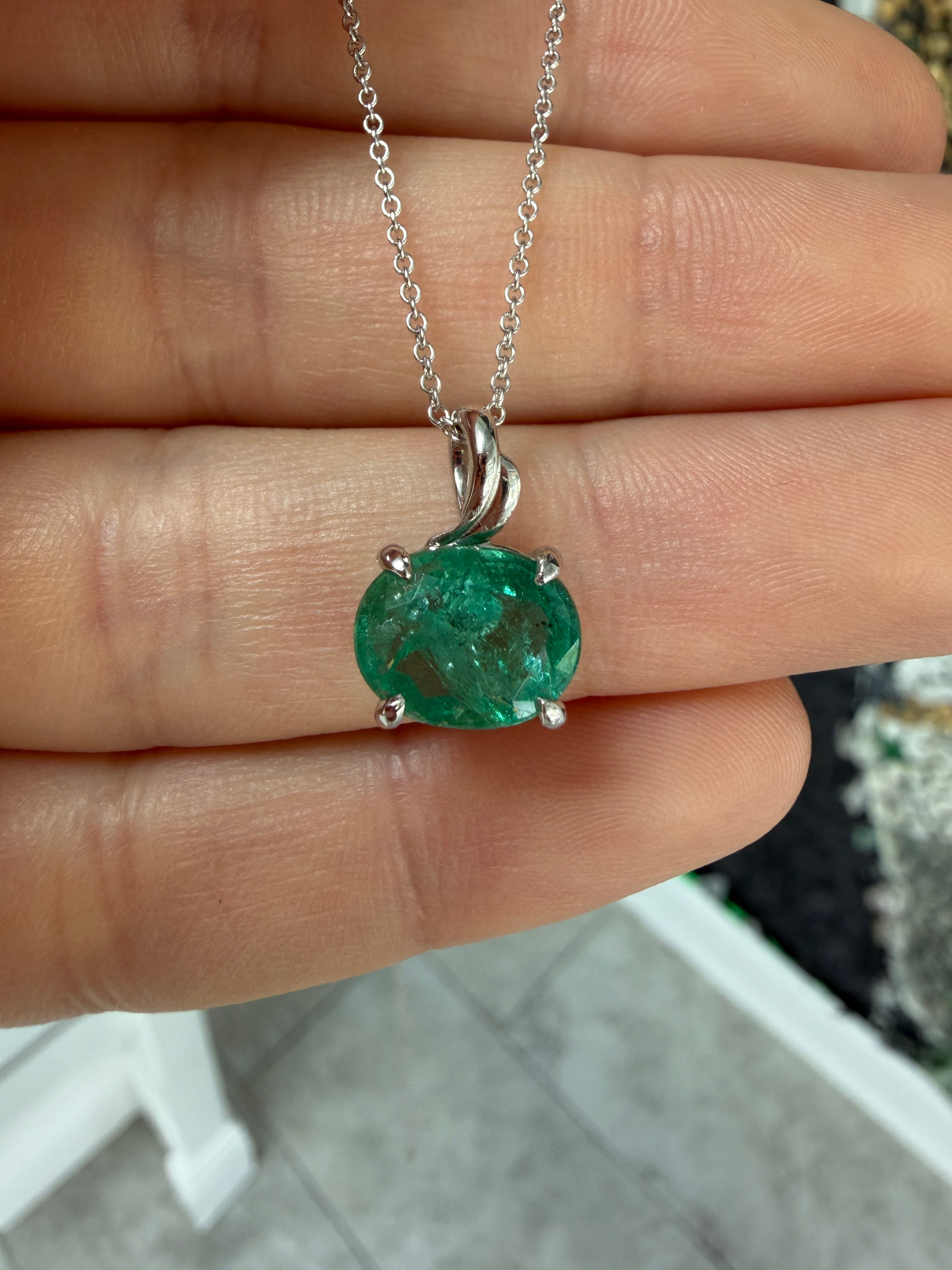 Earthy 2.60ct oval emerald leaf pendant necklace on 14K white gold, featuring an east-to-west cut and solitaire design.