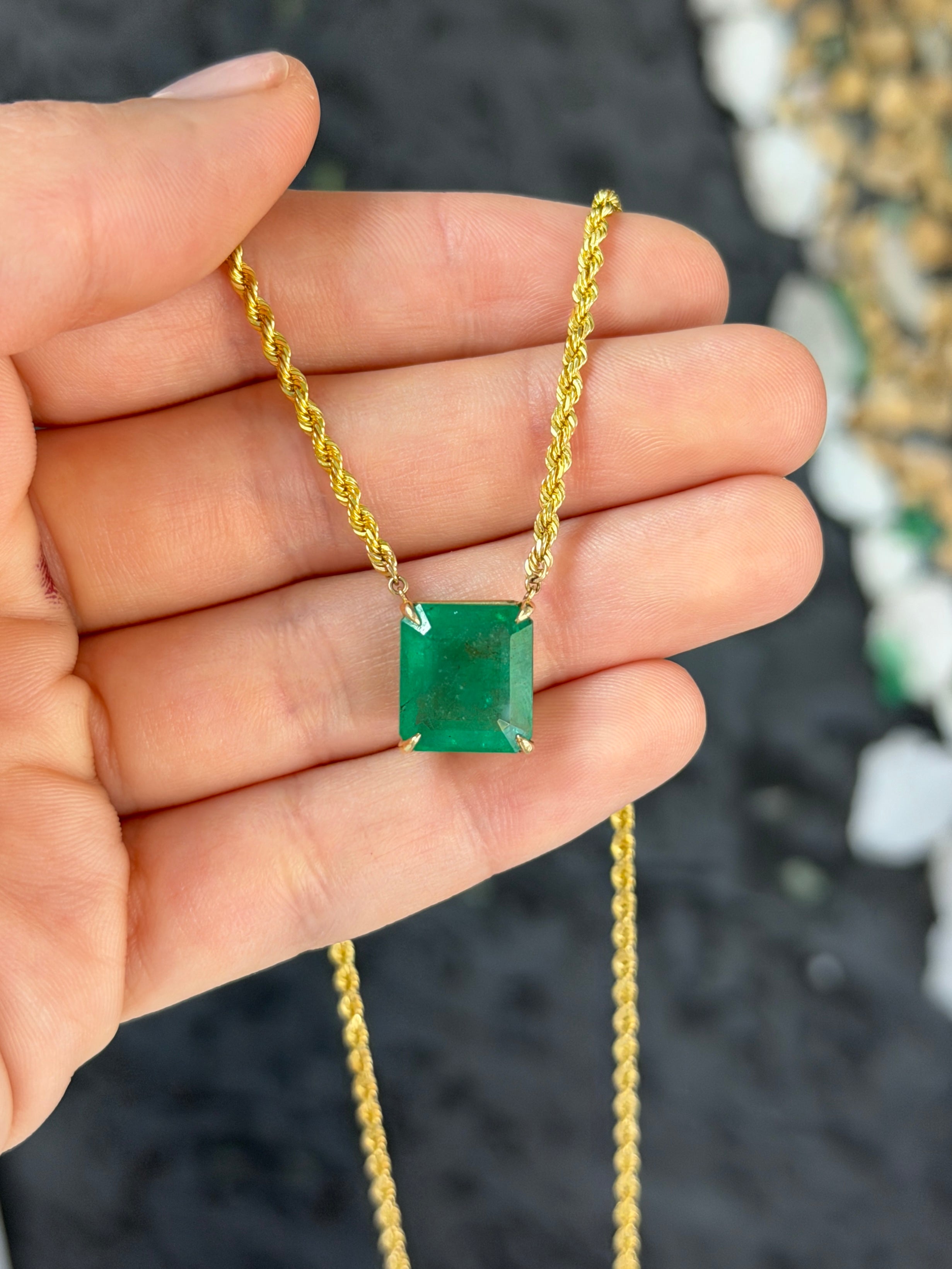 14K emerald cut emerald solitaire necklace with 10.38ct gemstone on a 20-inch rope chain, featuring a stationary design.