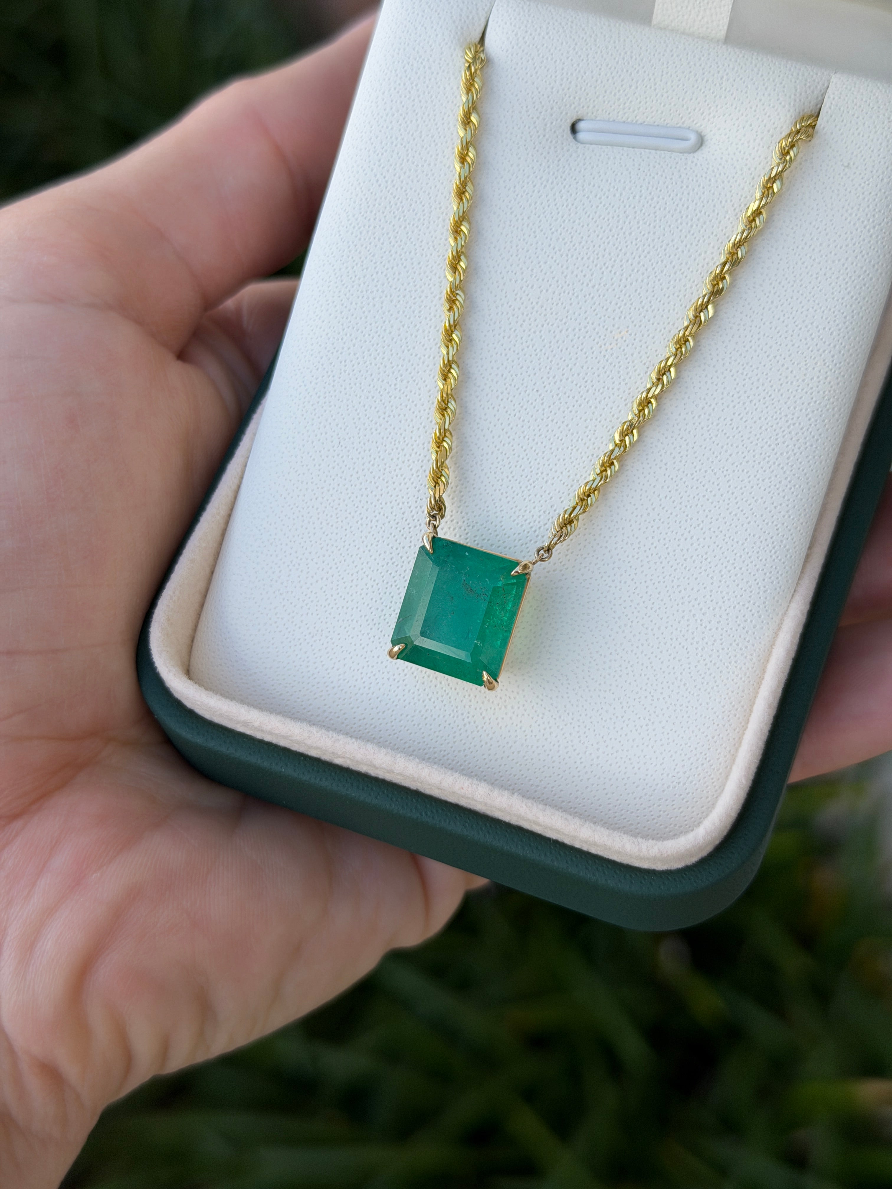14K emerald cut emerald solitaire necklace with 10.38ct gemstone on a 20-inch rope chain, displayed against a neutral background.