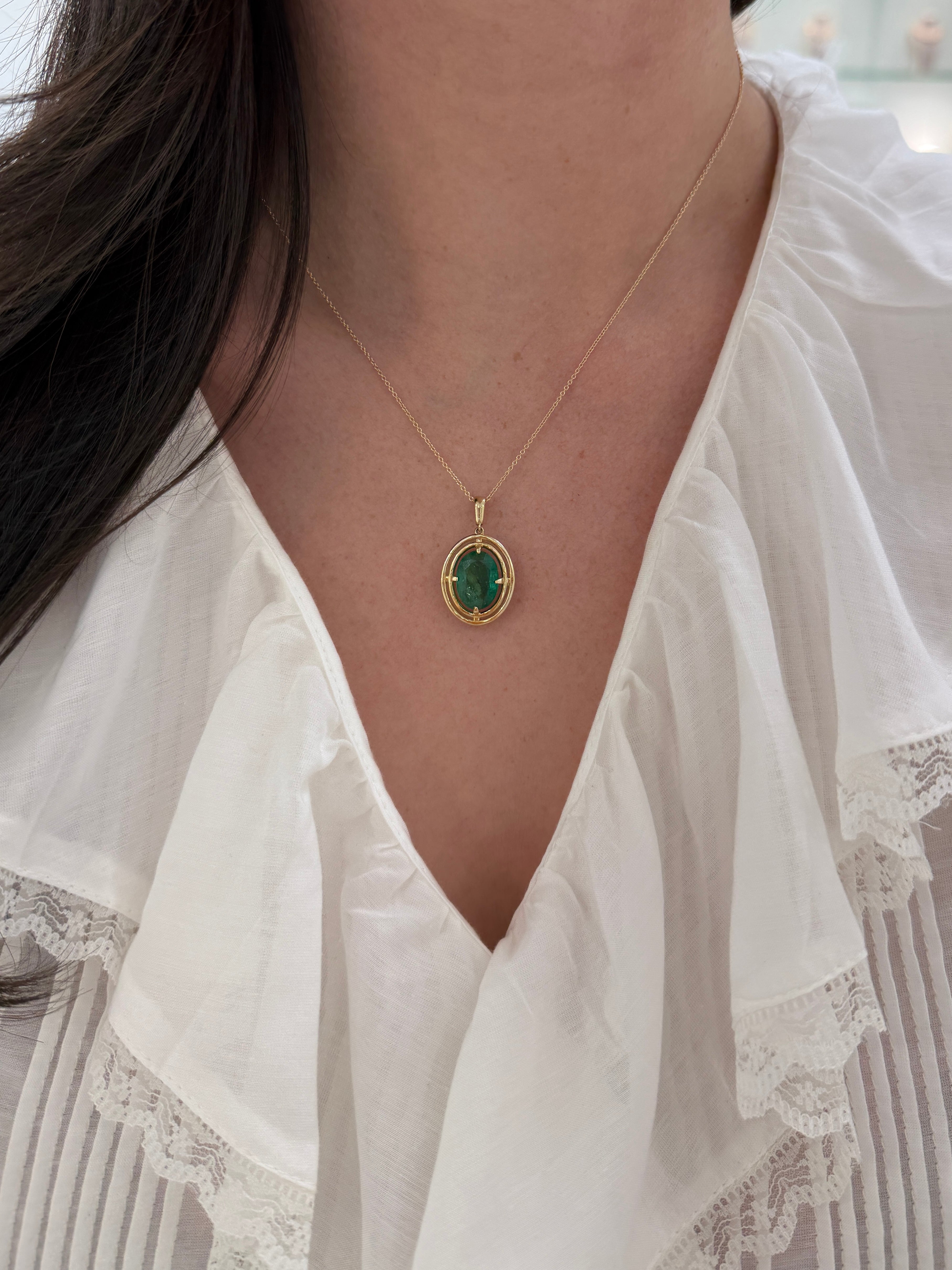Ciondolo solitario con smeraldo ovale e doppia cornice a corona in oro giallo 14 carati, con montatura flottante a quattro griffe realizzata da JR Colombian Emeralds.