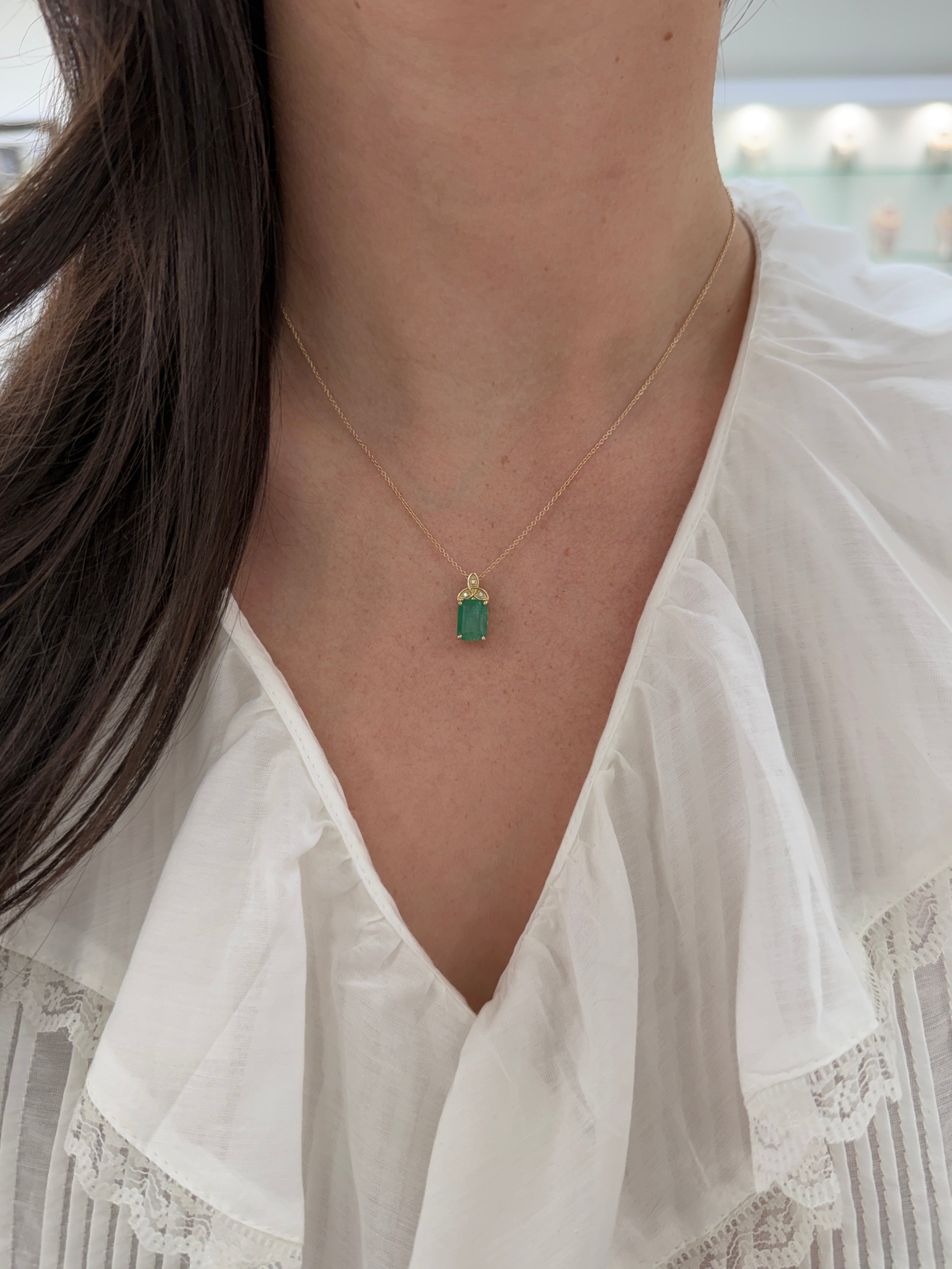 14K yellow gold Trinity knot necklace with a 2.12tcw emerald solitaire from JR Colombian Emeralds, featuring intricate knot design and gemstone.