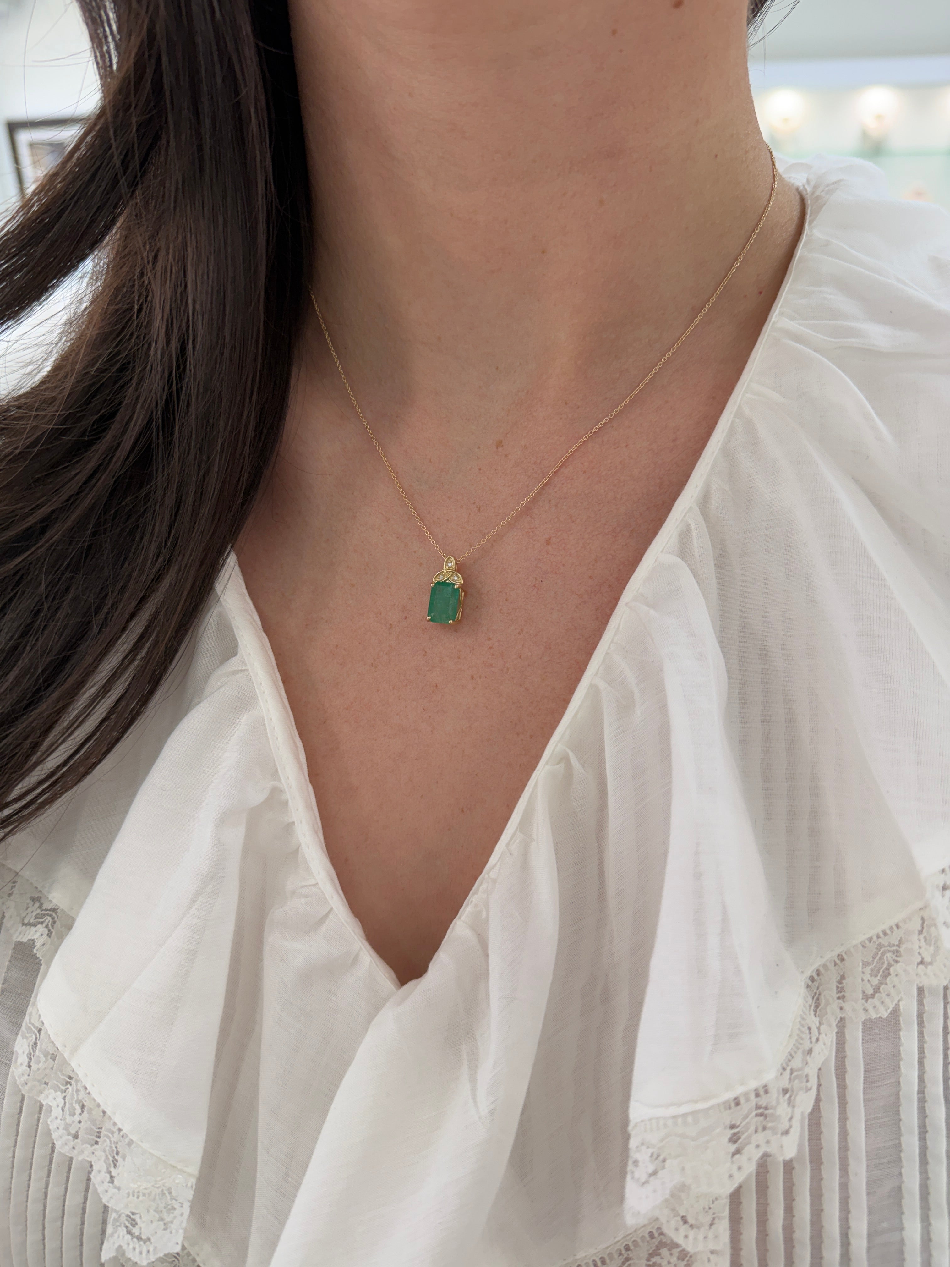 14K yellow gold Trinity knot emerald solitaire necklace with 2.12 tcw from JR Colombian Emeralds, featuring a central emerald gemstone.