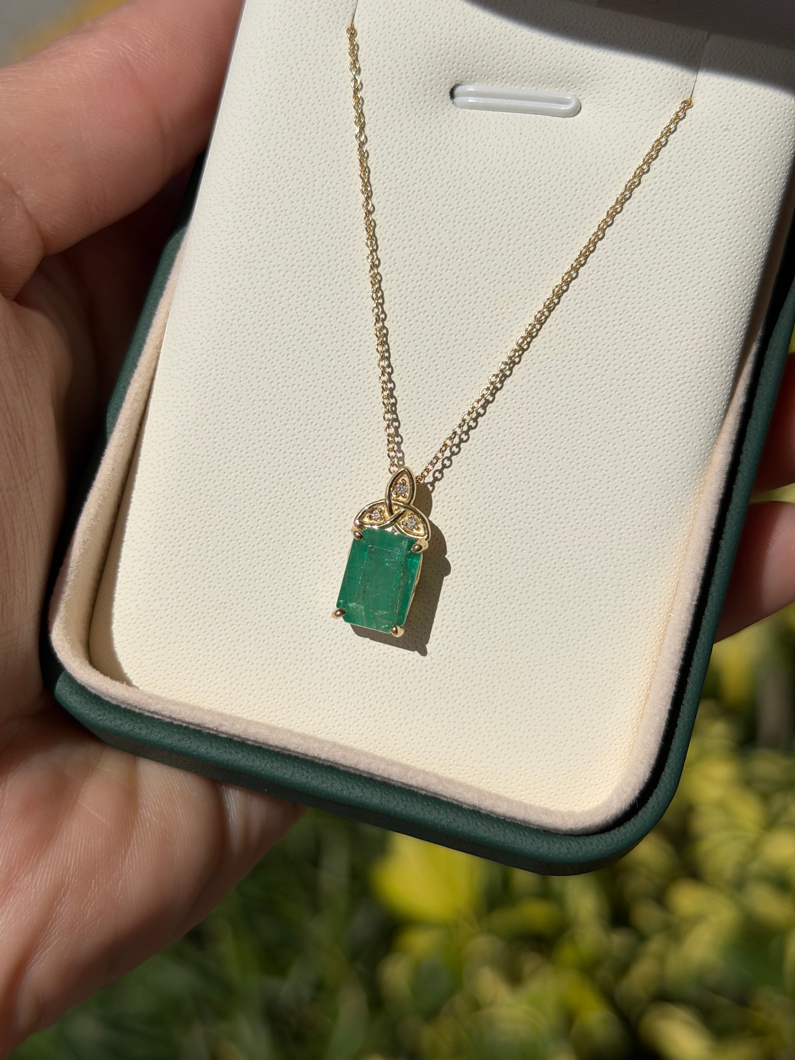 14K yellow gold Trinity knot emerald solitaire necklace with 2.12 carats, featuring a central emerald gemstone.