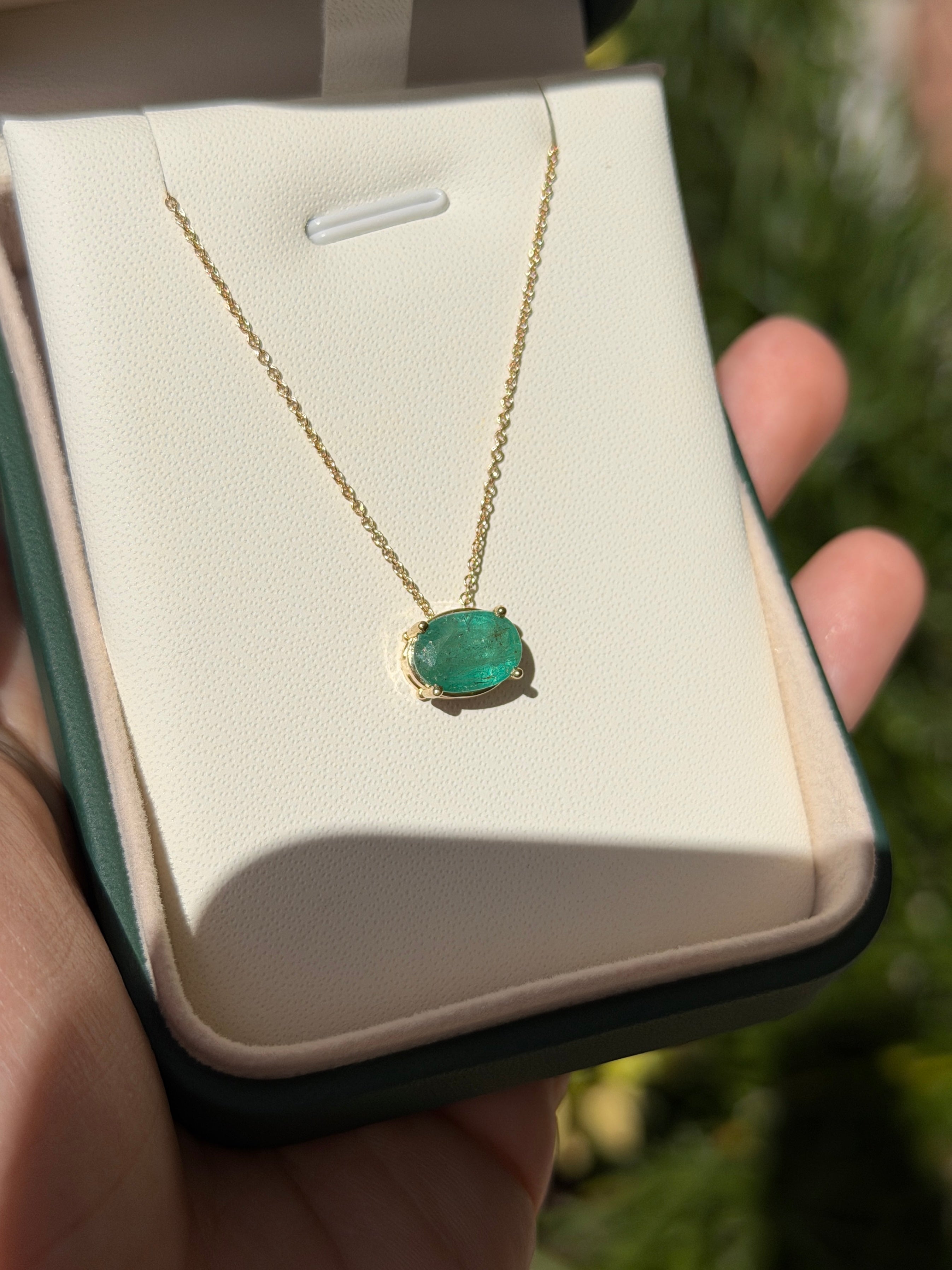 14K gold solitaire emerald oval slider necklace with a 2.15 carat emerald pendant, featuring a sleek and elegant design.