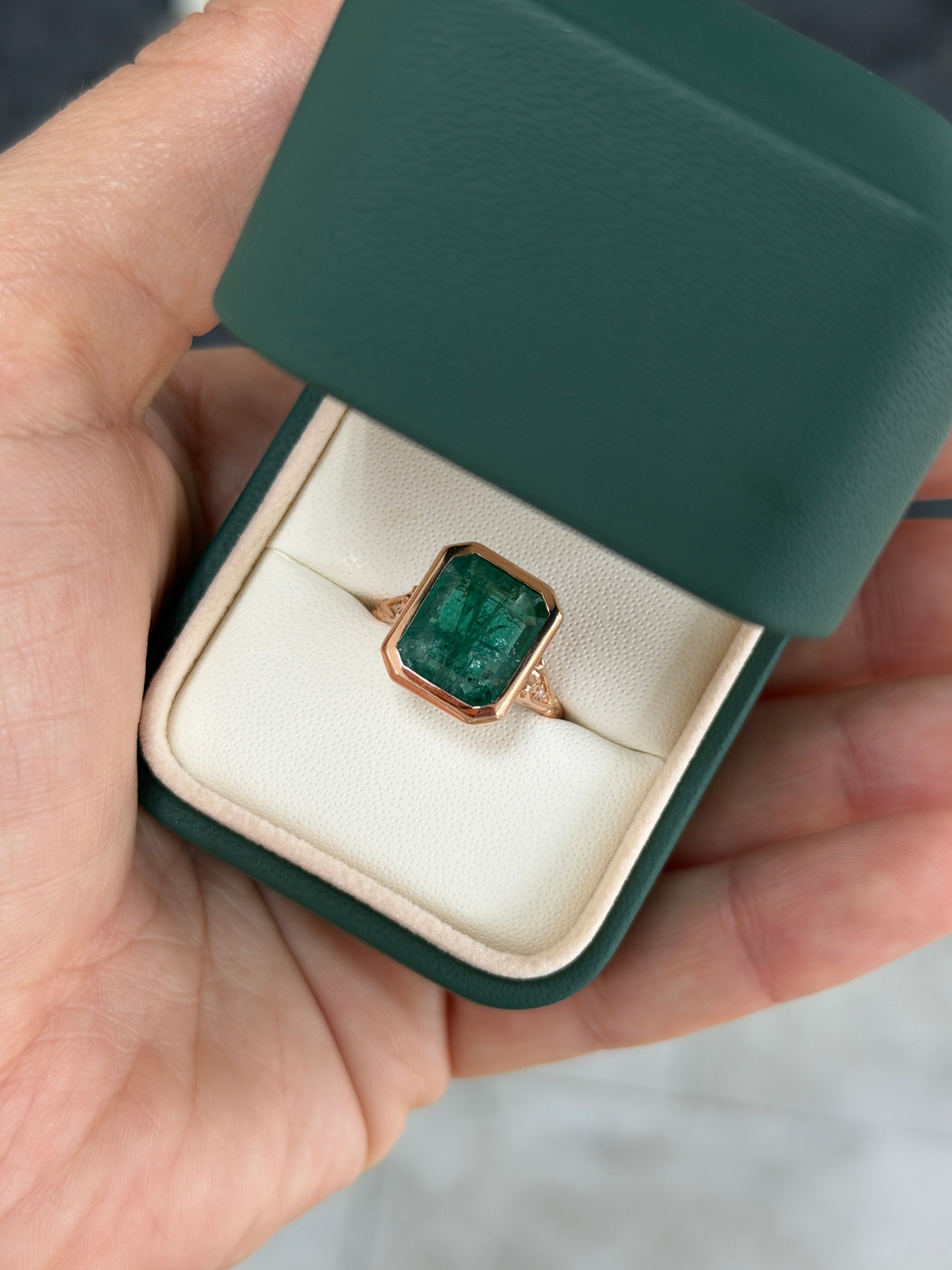 Vintage-inspired 14K rose gold emerald bezel ring with diamond shank and scroll basket detail by JR Colombian Emeralds.