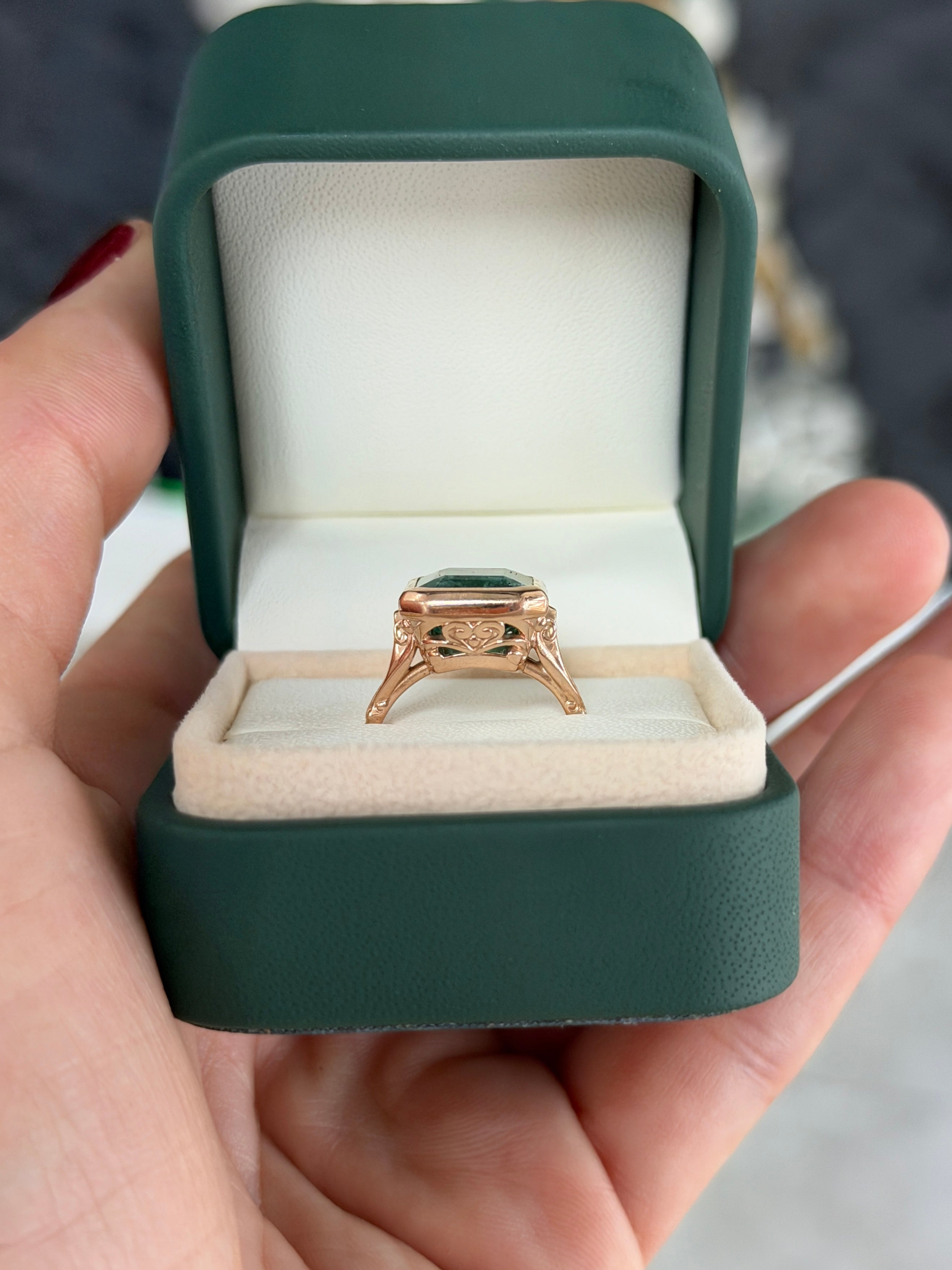 Vintage-inspired 14K rose gold emerald bezel ring with diamond shank and scroll basket detail, featuring 6.20 tcw of emeralds.