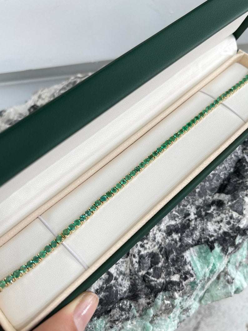 Medium dark green round cut emerald tennis bracelet with 14K setting by Colombian Emerald, unisex jewelry, close-up view.