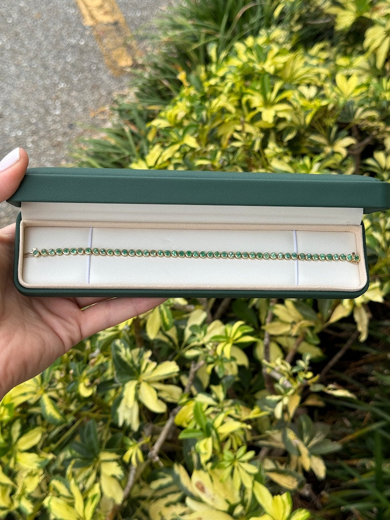 Unisex emerald tennis bracelet with round cut green emeralds set in 14K yellow gold bezel, Colombian Emerald brand.